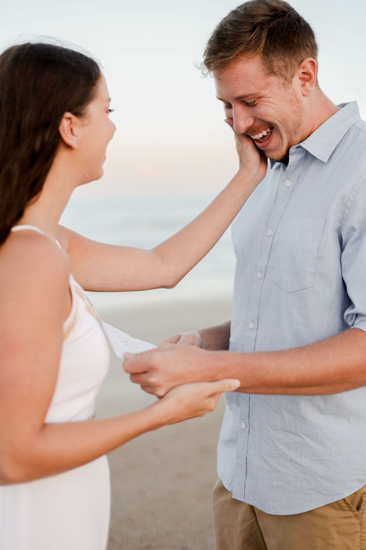 An emotional proposal moment captured on the beach at sunset.