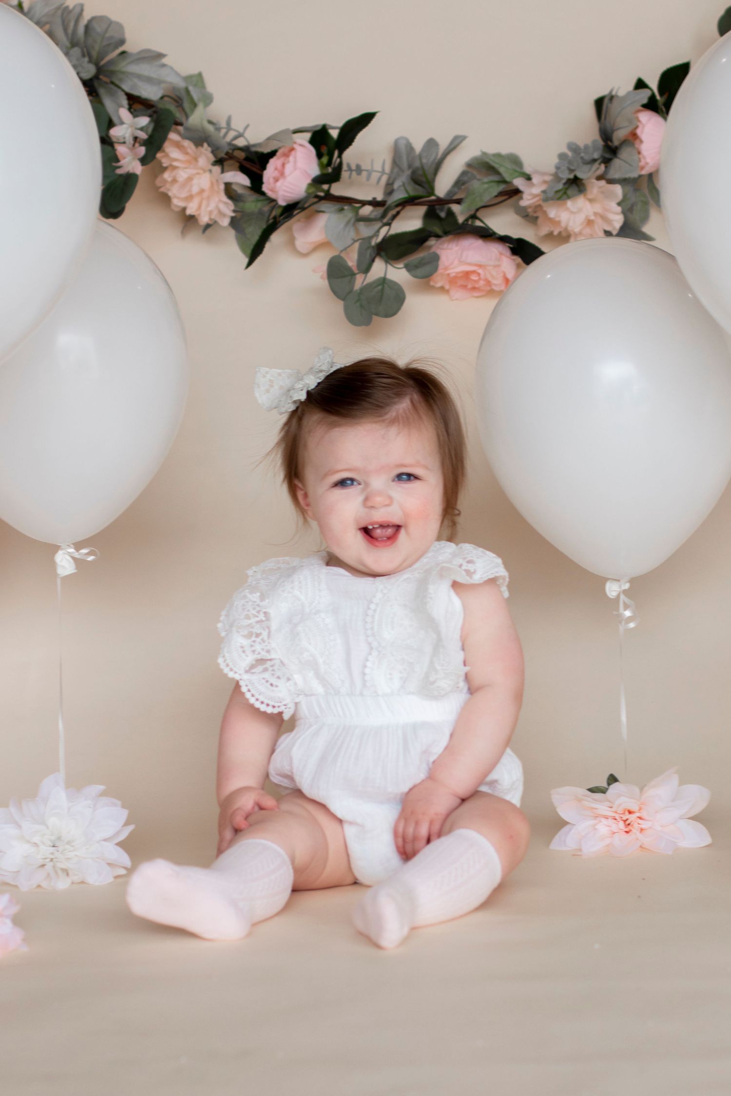 Studio photoshoot setup with white balloons and pink floral decorations.
