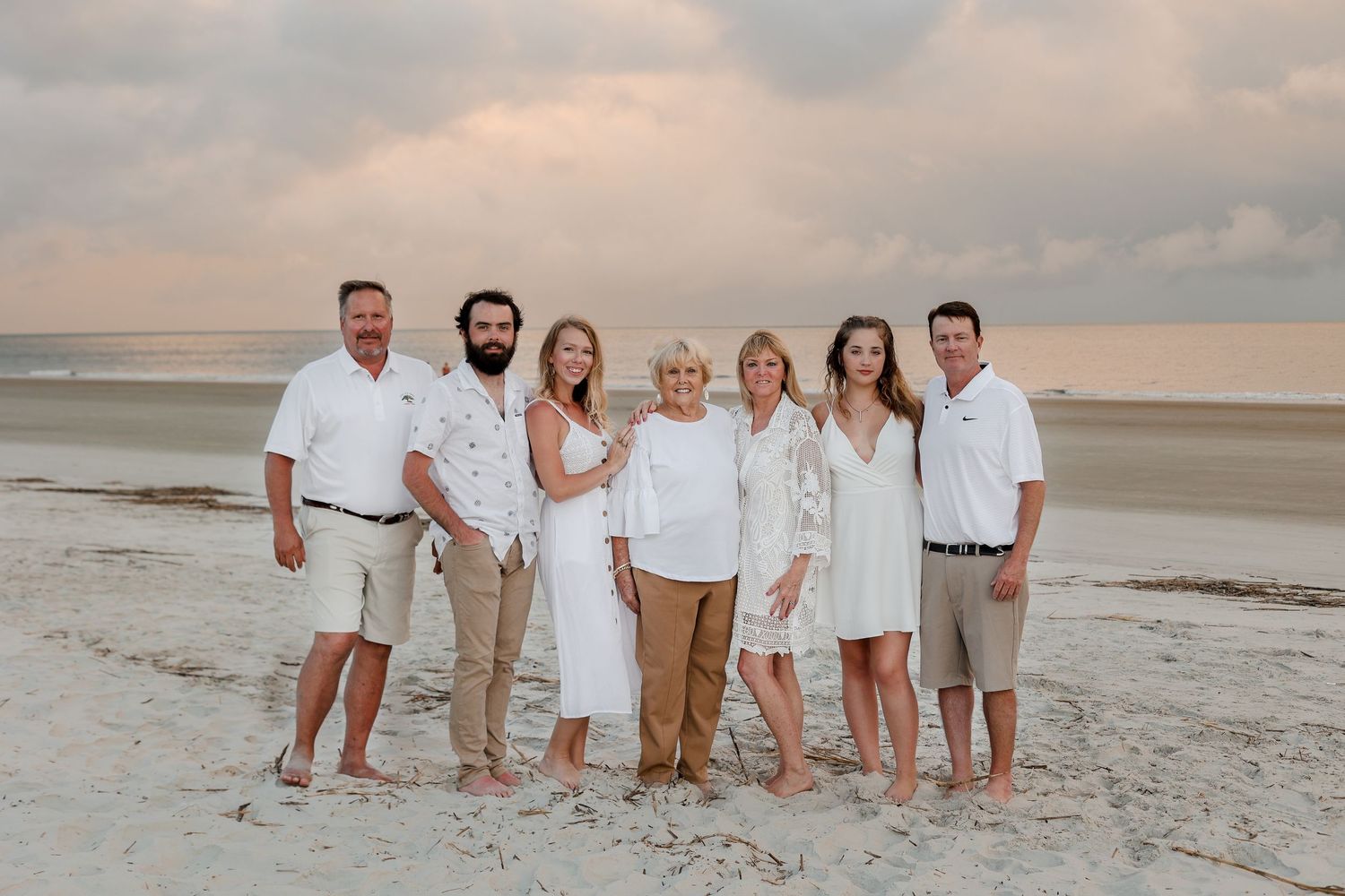 Beach group photo with everyone wearing coordinated white and khaki outfits.