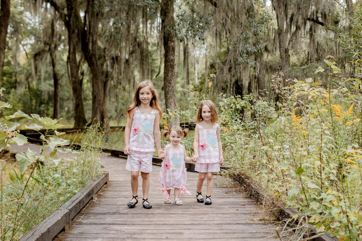 Children walking on a tree-lined path through a lush garden setting.