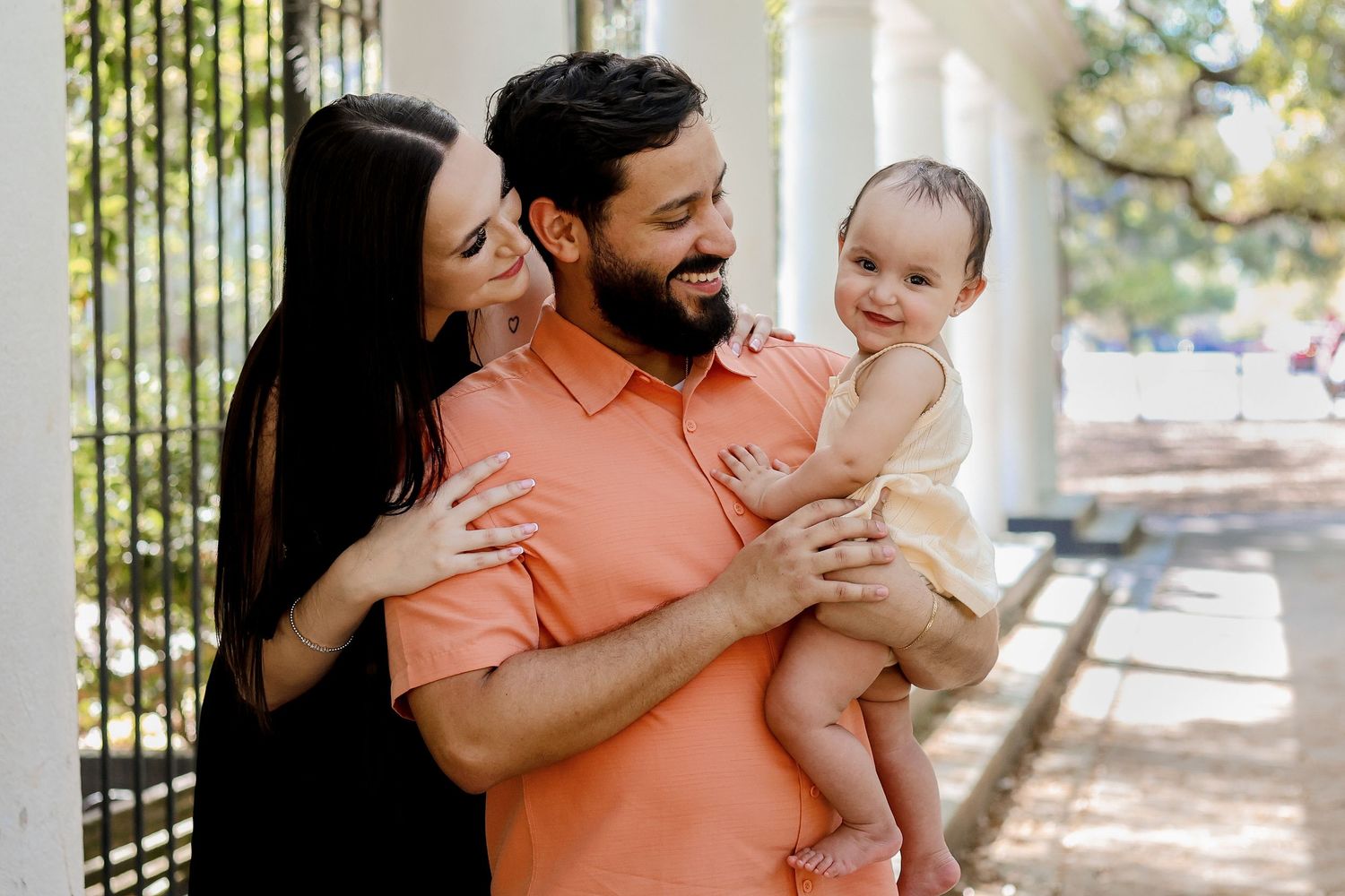 Family sharing tender moments on a sunny porch with white columns.
