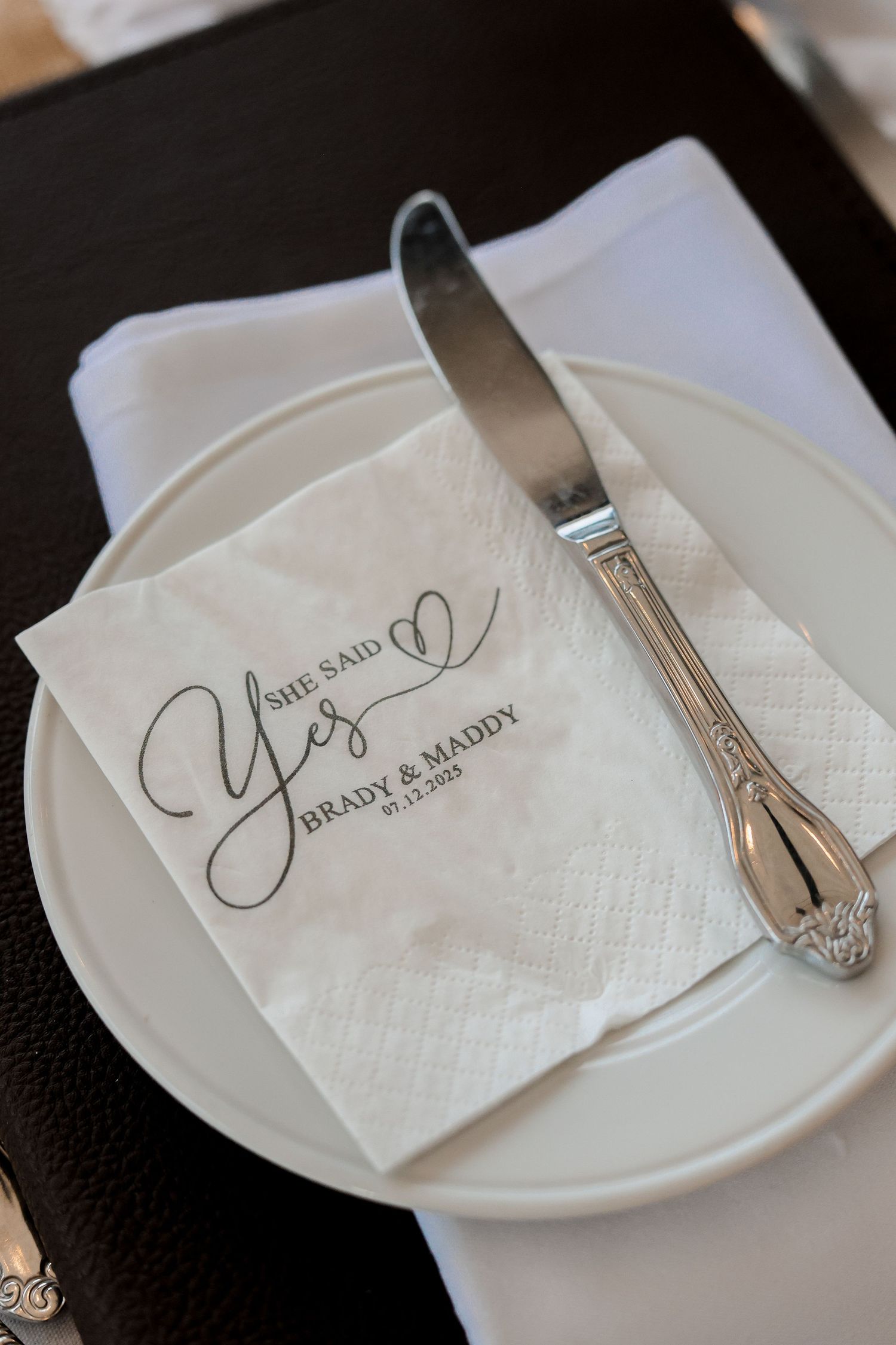 Elegant white napkins with monogrammed initials displayed on plates with decorative silverware at a formal place setting.