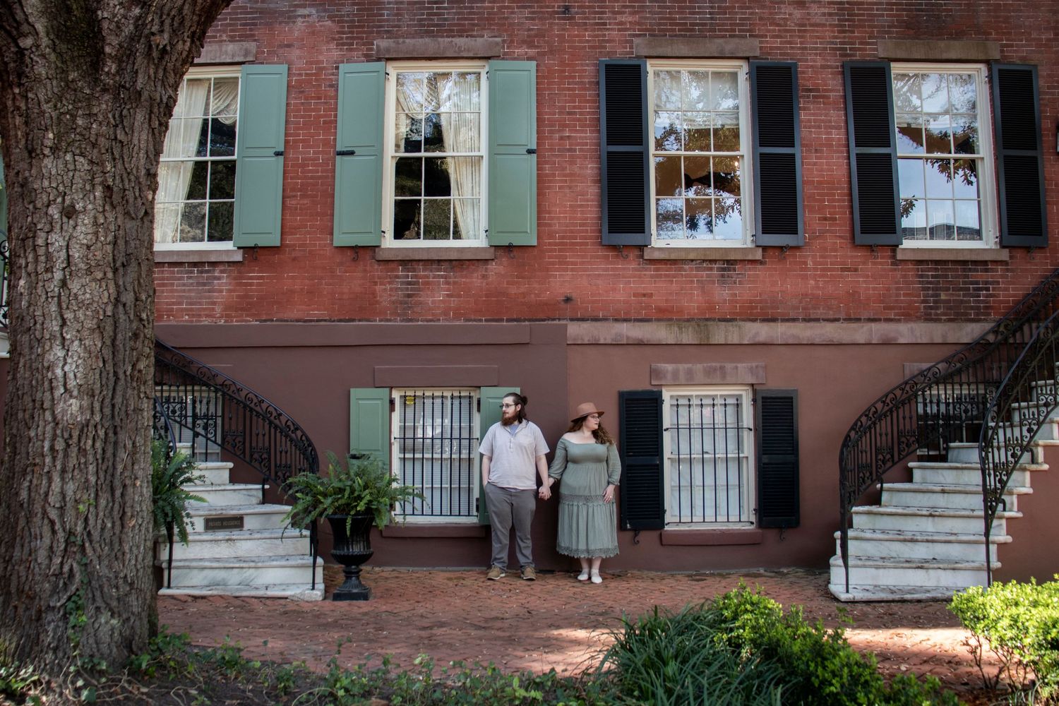 Historic brick buildings with teal shutters and classic architectural details line a cobblestone street.