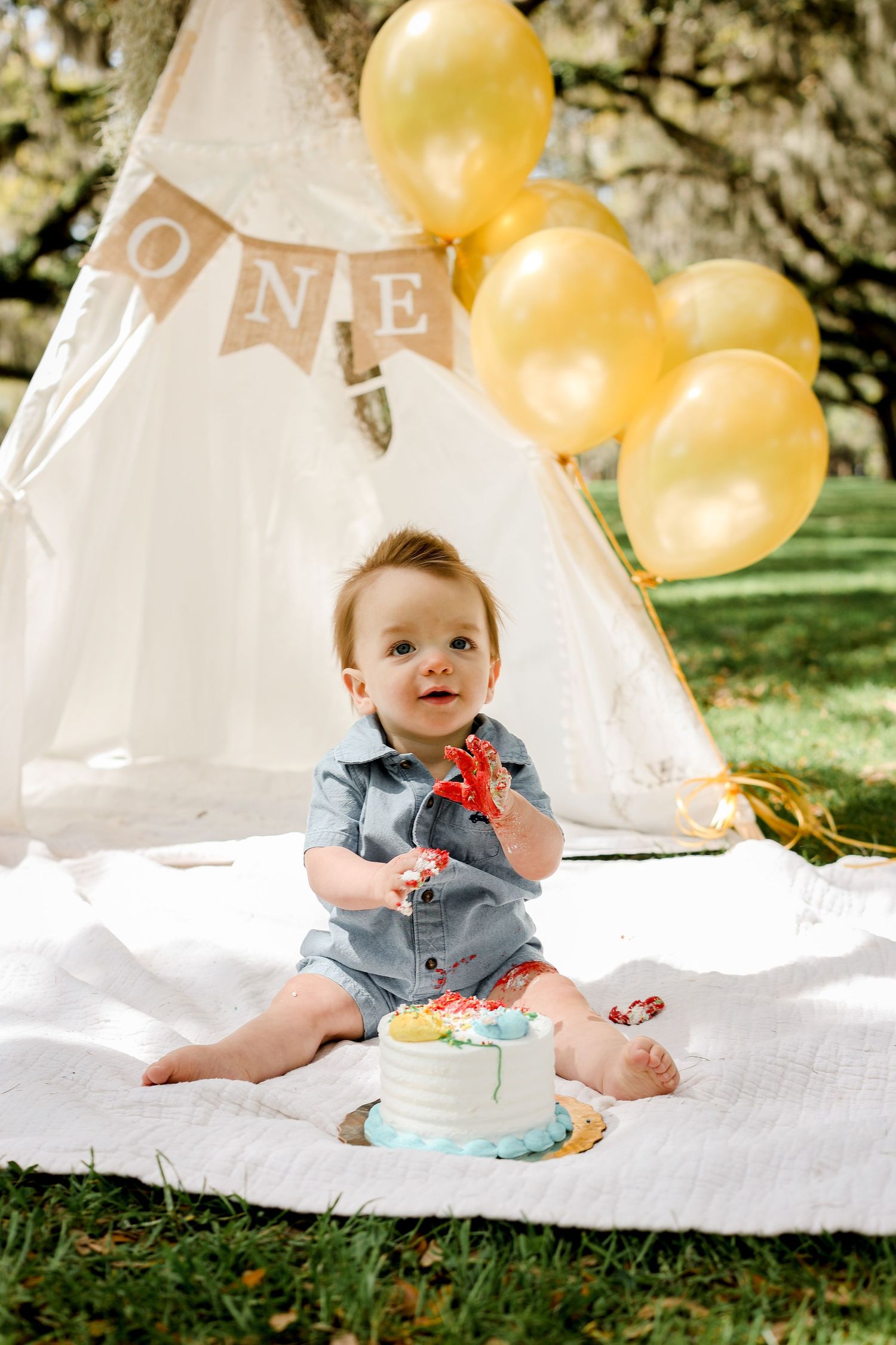 First birthday cake smash session with white teepee and yellow balloon decorations.
