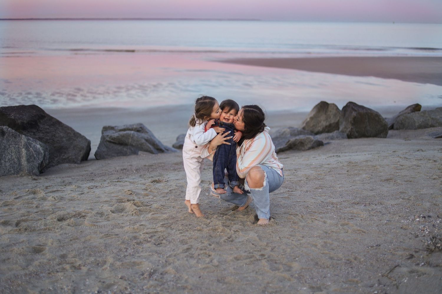 Family enjoying quality time together on a sandy beach at dusk.