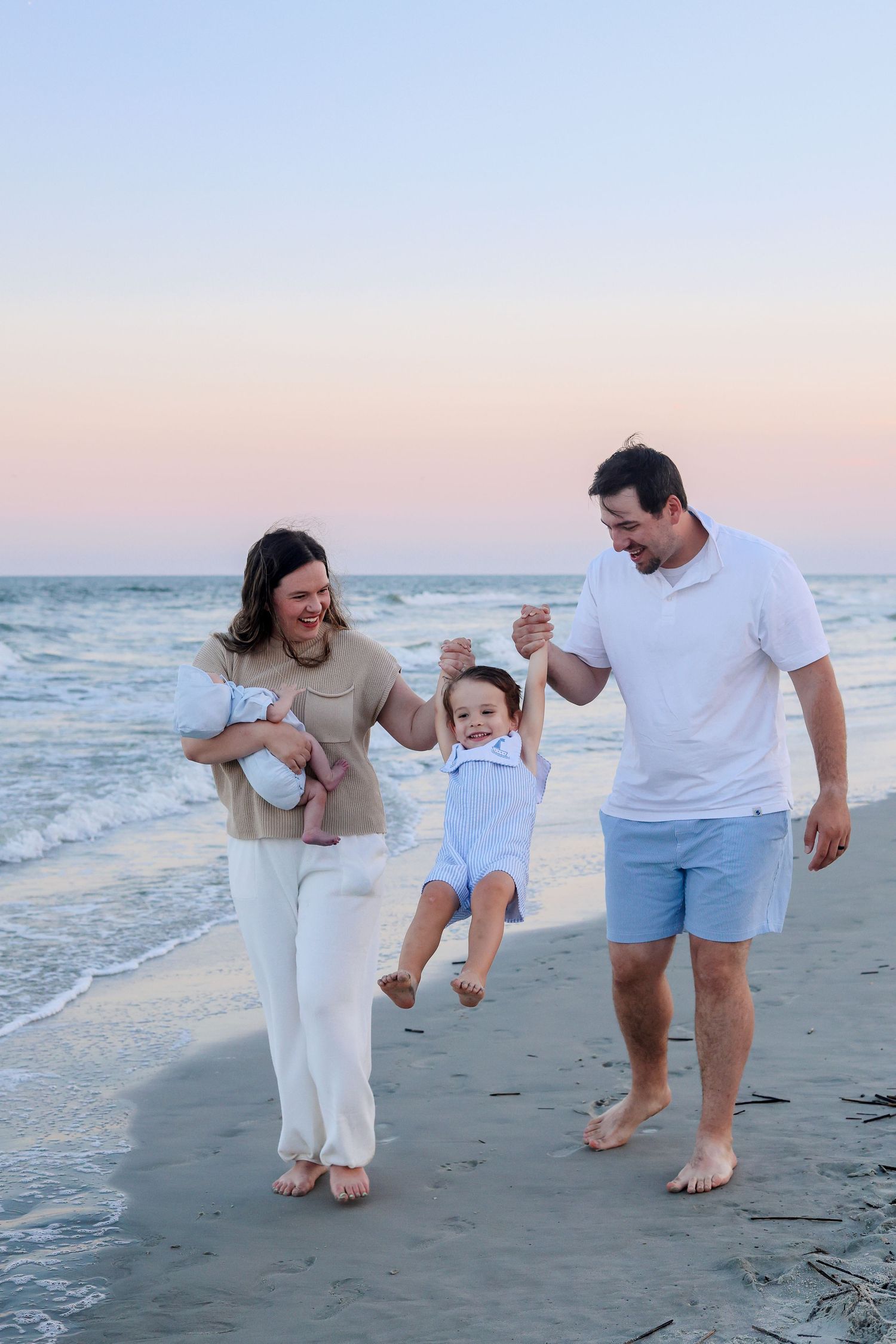 Family having fun and playing together on the beach during a sunset photoshoot.