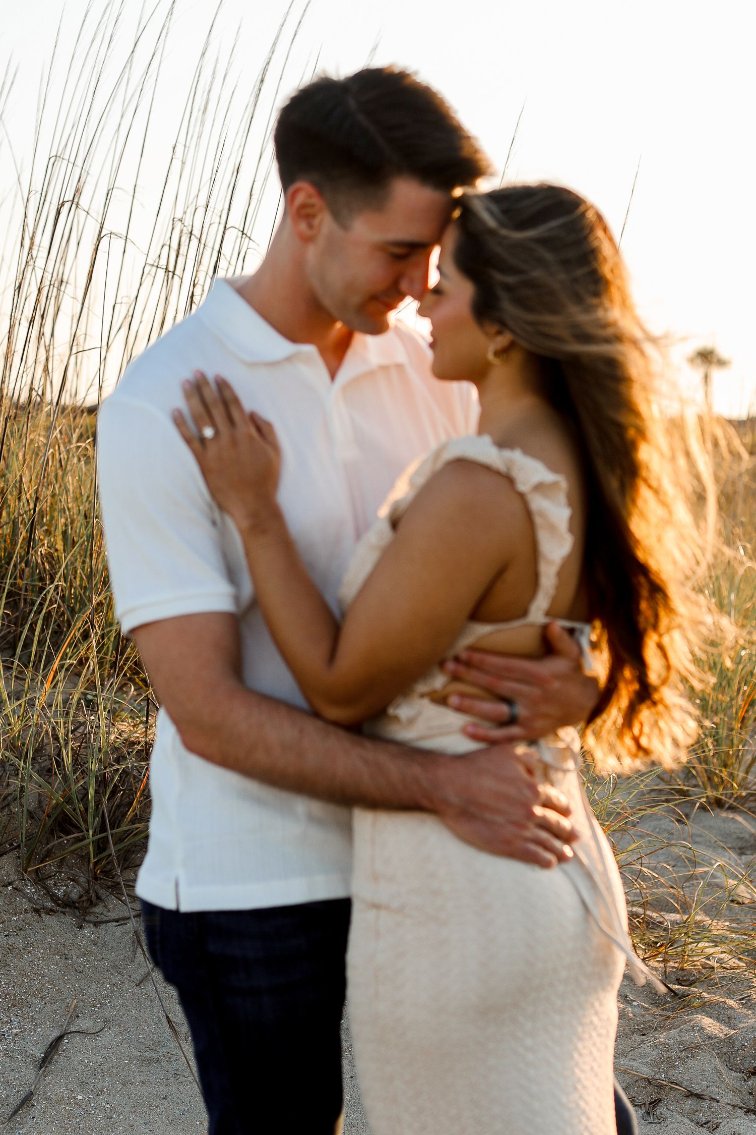 Romantic sunset portrait among beach grass with golden hour lighting.