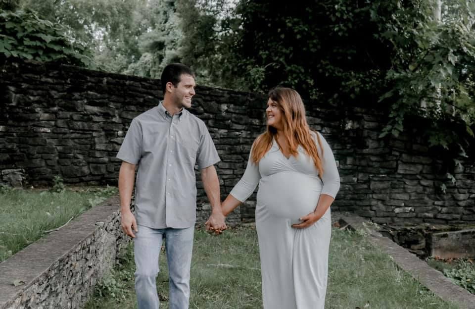 A couple poses together on a stone path surrounded by lush greenery.