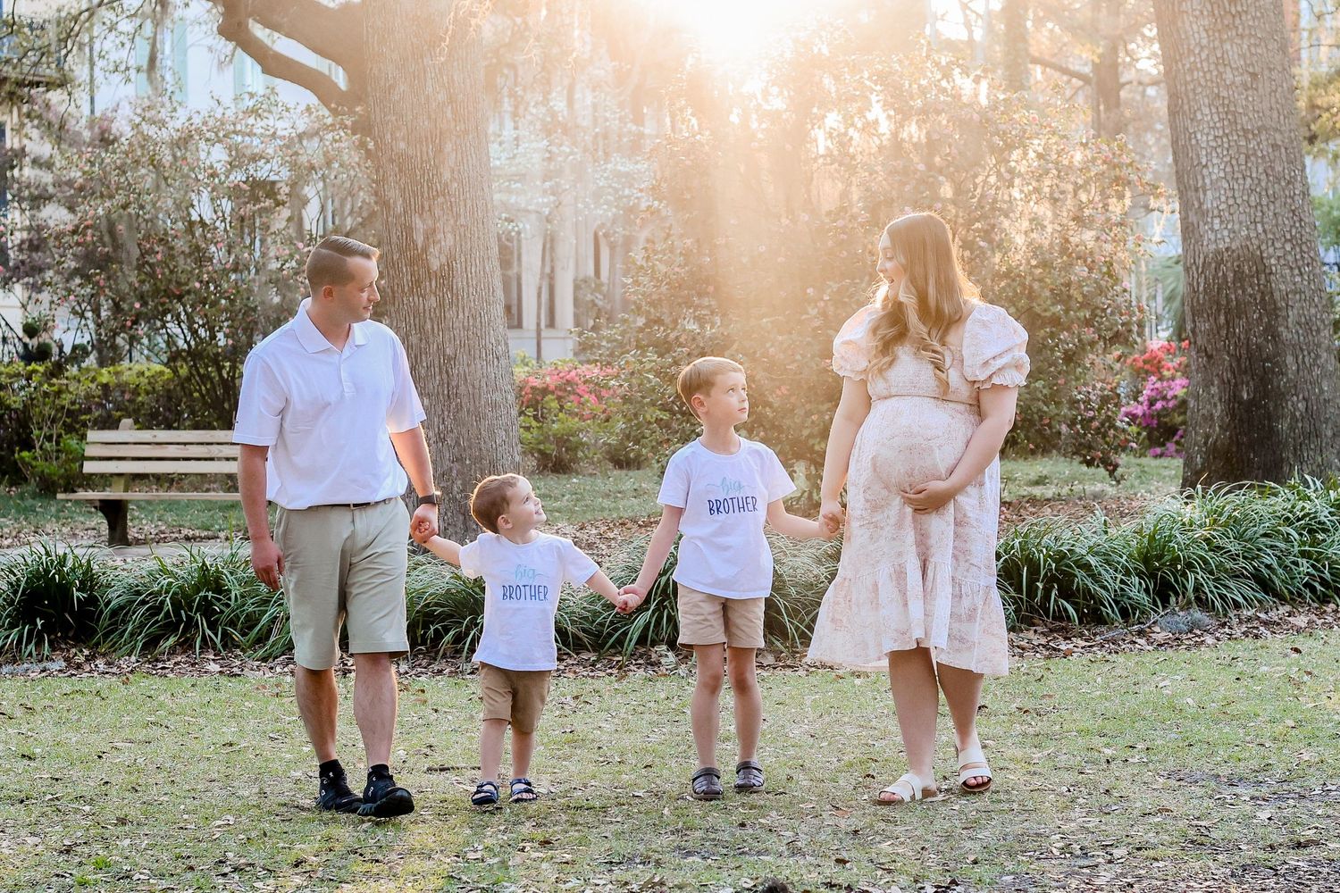 A family walking together at sunset in a garden with blooming azaleas.