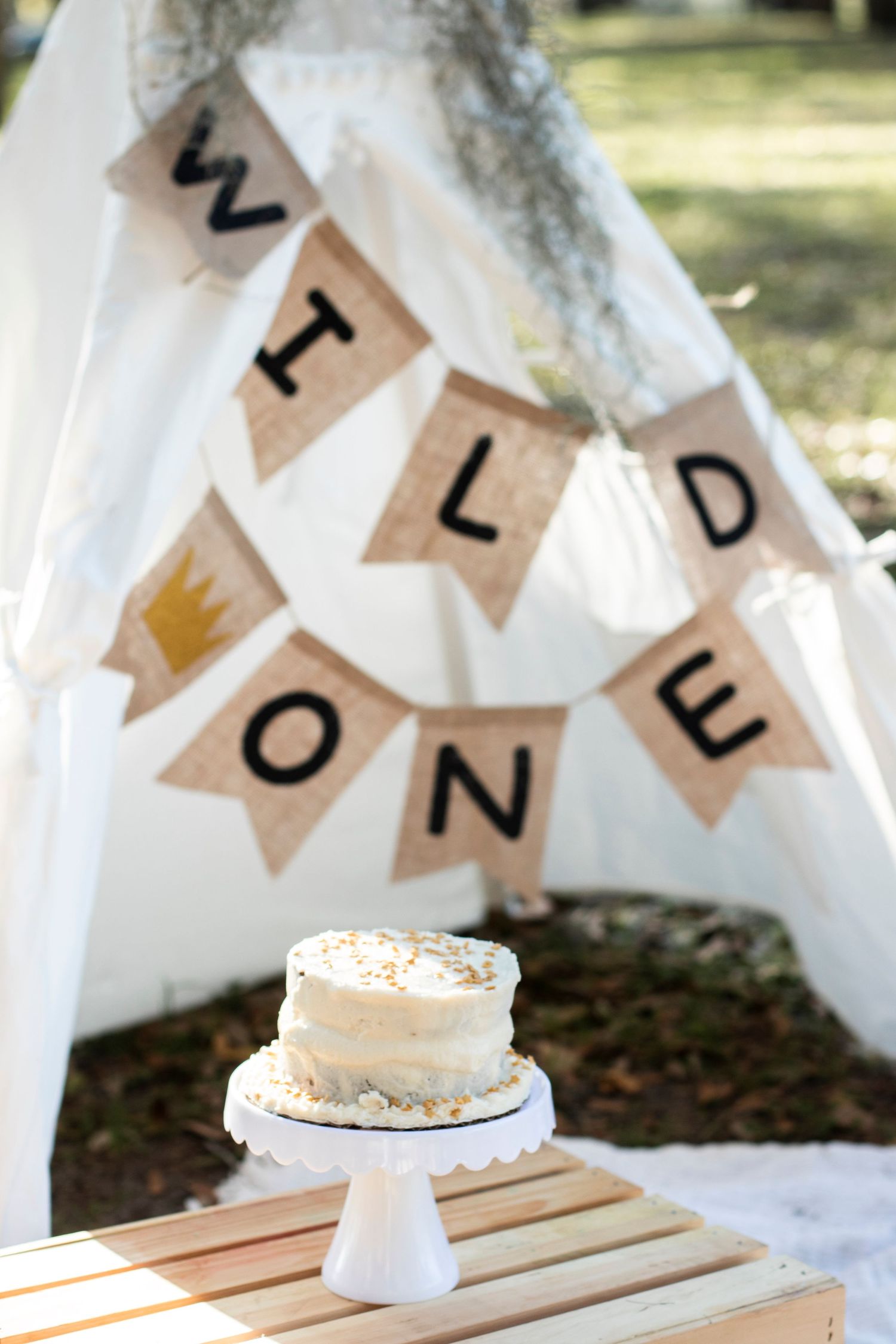 White cake display with decorative bunting banner strung above on white table.