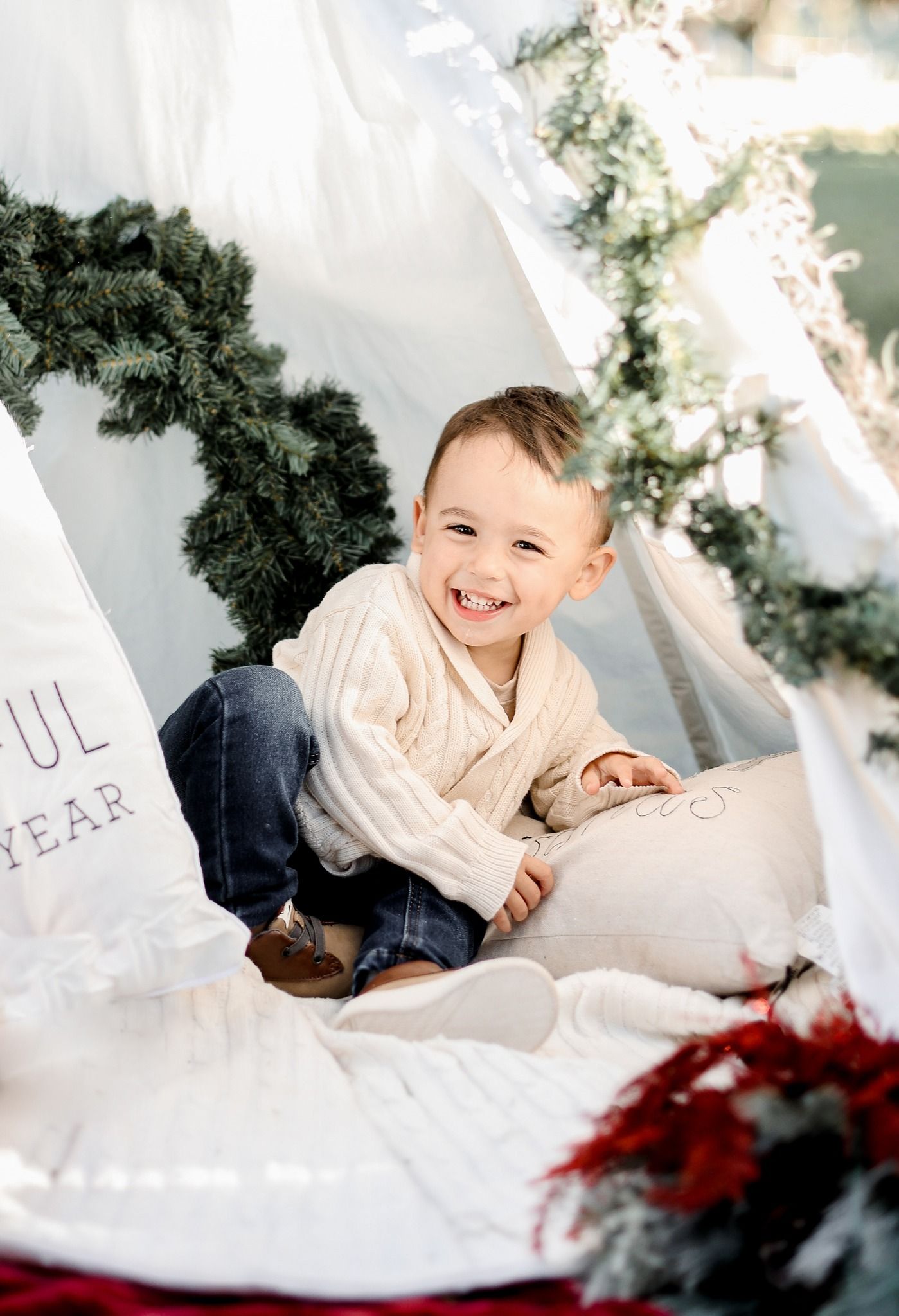 A festive holiday setup with white pillows and evergreen decorations creating a cozy winter scene.