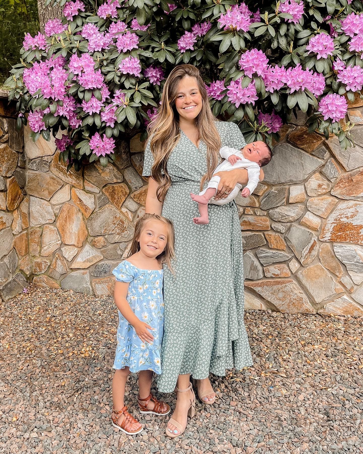 Family photoshoot setup with pink azalea flowers against stone wall backdrop.