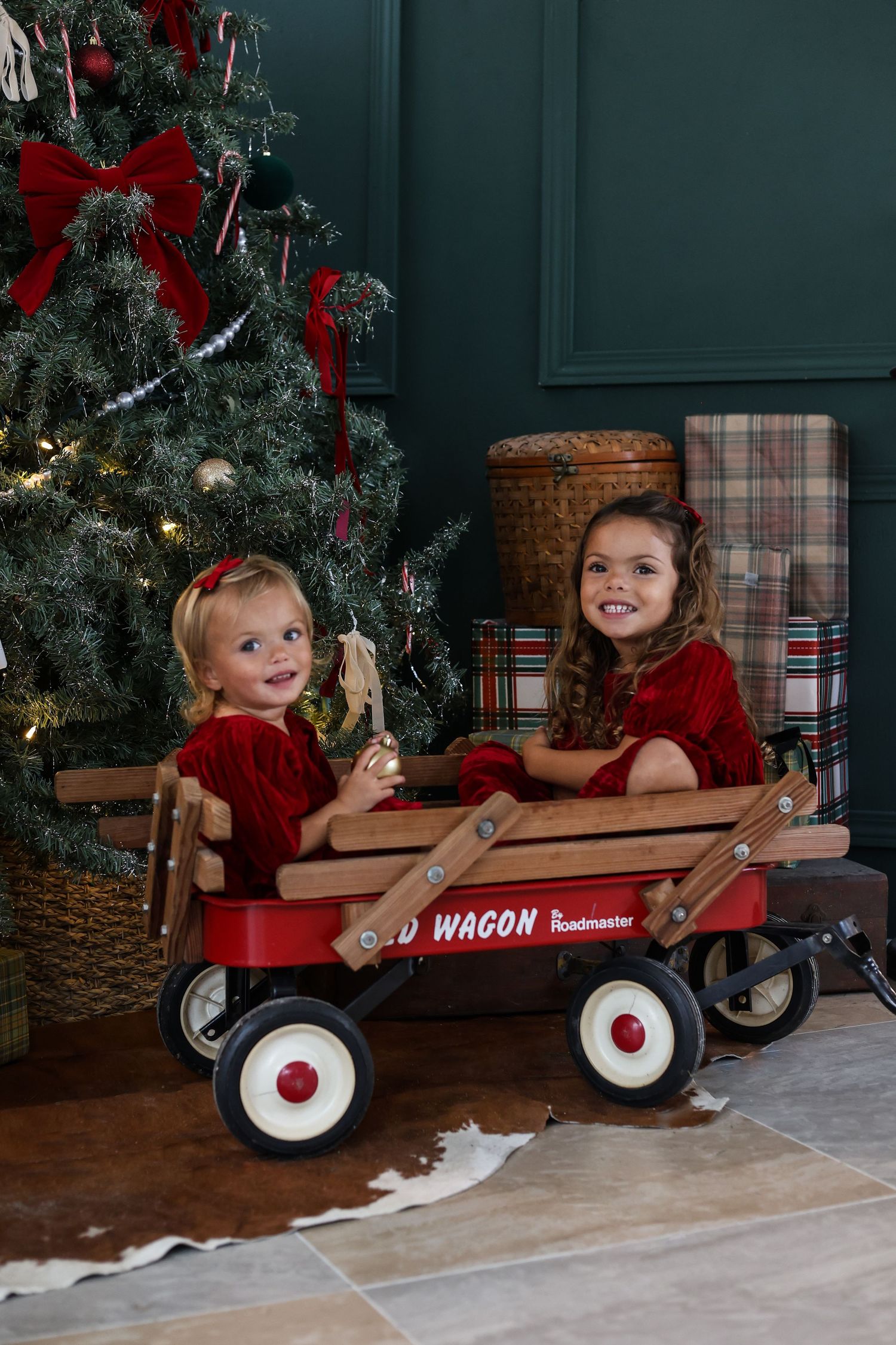 Four sequential photos showing a Radio Flyer wagon with festive Christmas decor and decorative elements by a holiday tree.
