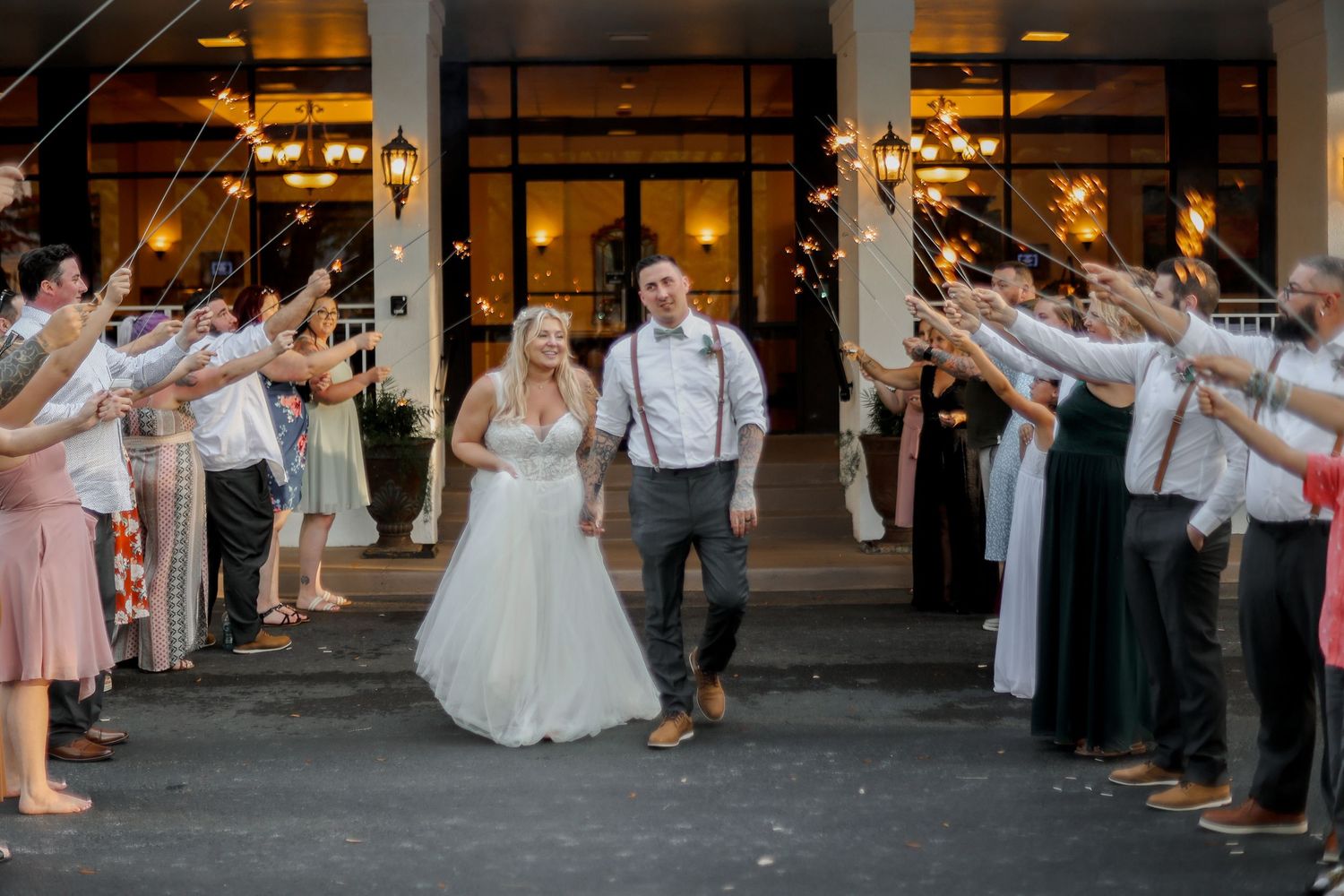 Wedding guests forming a sparkler exit tunnel for the newlyweds outside a venue.