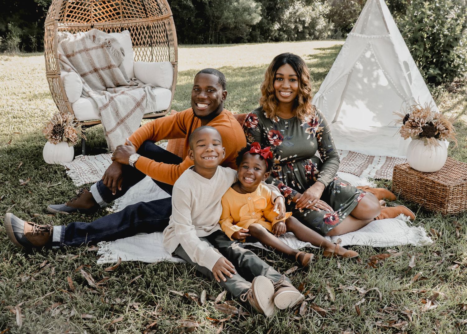 Outdoor family photoshoot scene with teepee tent and natural lighting under trees.