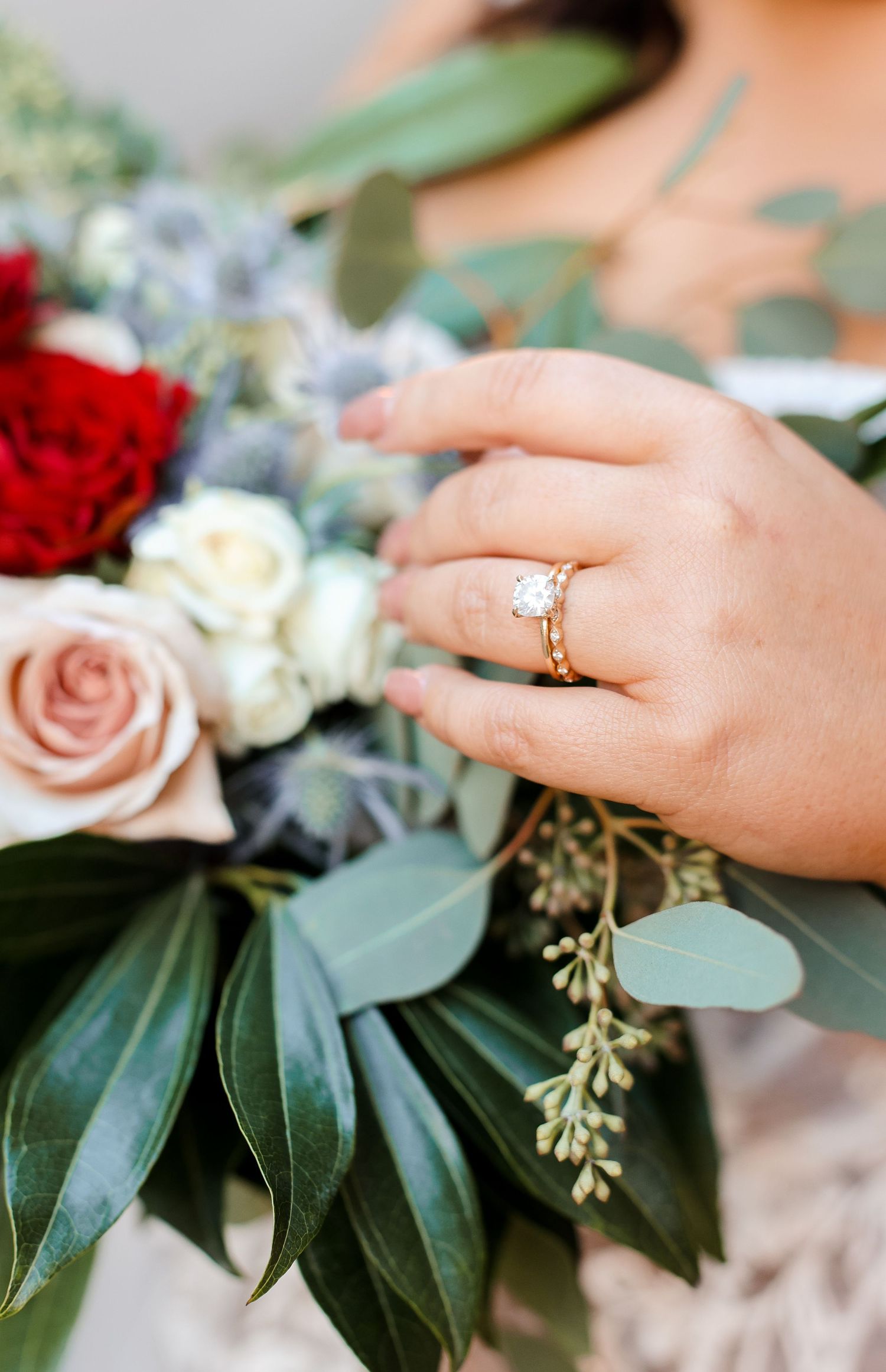 Close-up of wedding rings and floral details with eucalyptus leaves.