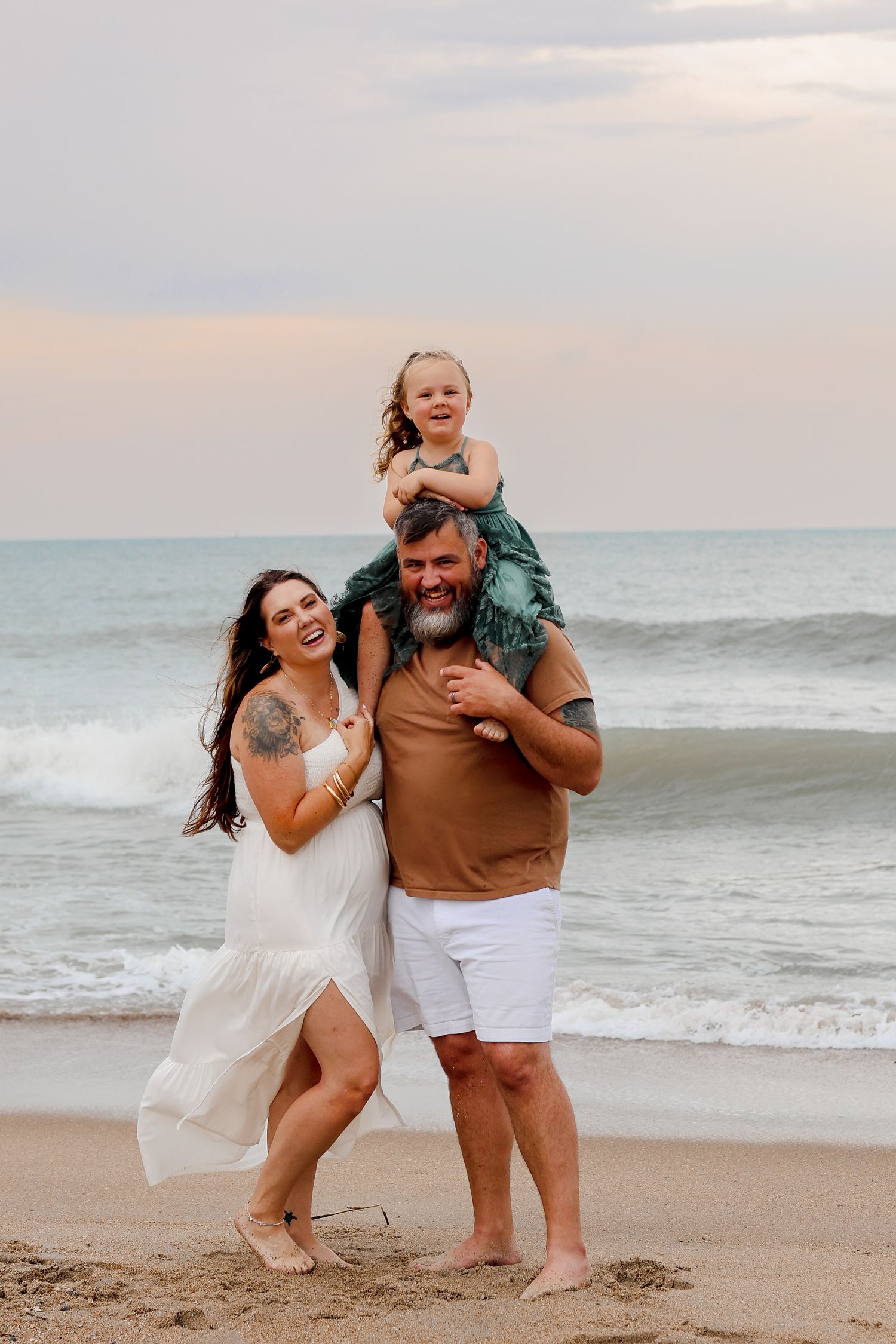 Family enjoying sunset at beach with playful poses.