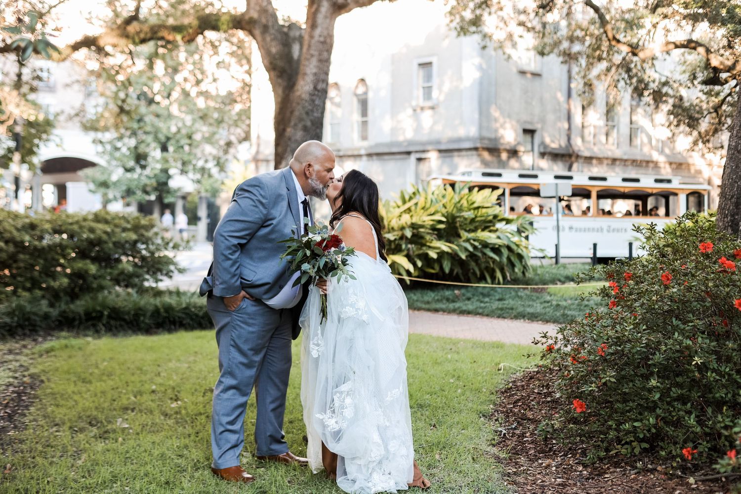 Wedding couple shares intimate moments in a garden setting with historic architecture.