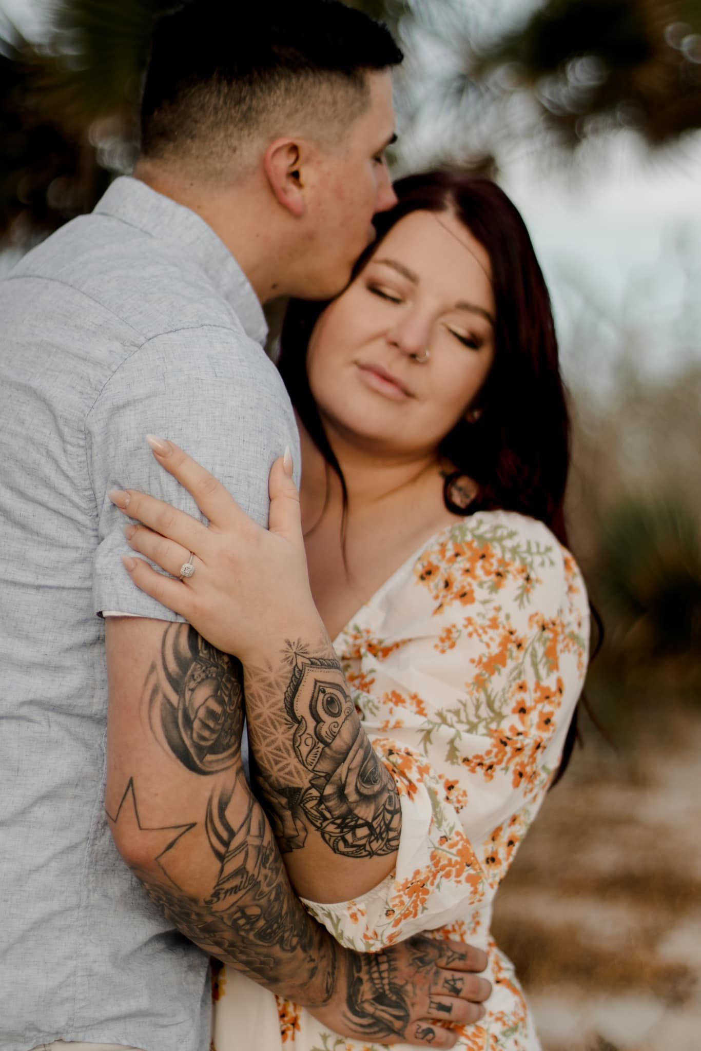 Intimate moment between couple during outdoor portrait session showing tattoo sleeve detail.