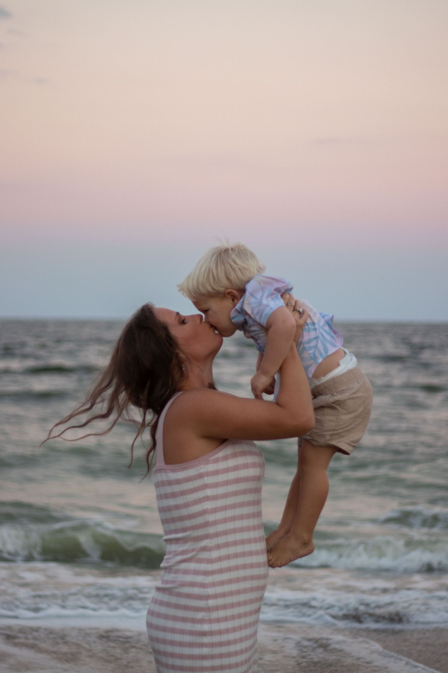 A tender moment between mother and child on the beach at sunset.