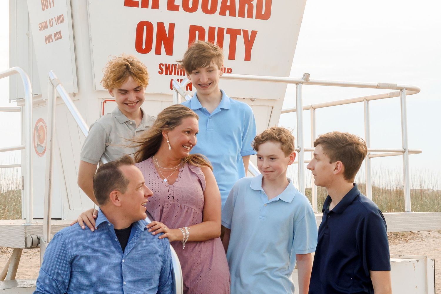 A casual family gathering near a lifeguard station on a sunny beach.