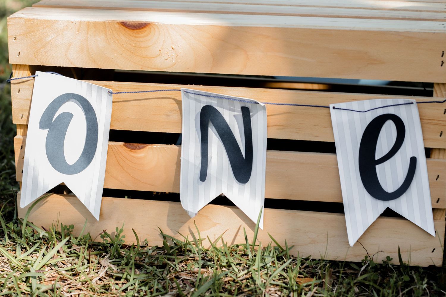Decorative ONE banner with blue banners on wooden crates for first birthday photoshoot.