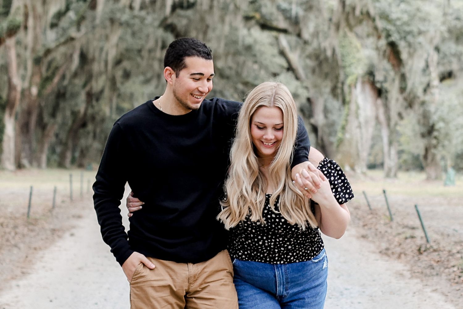 Couple laughing together during an outdoor photoshoot among moss-covered trees.
