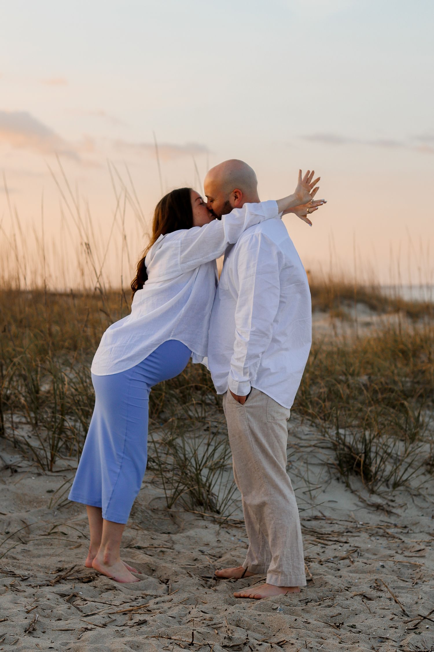 Loving moment captured on sand dunes at dusk.