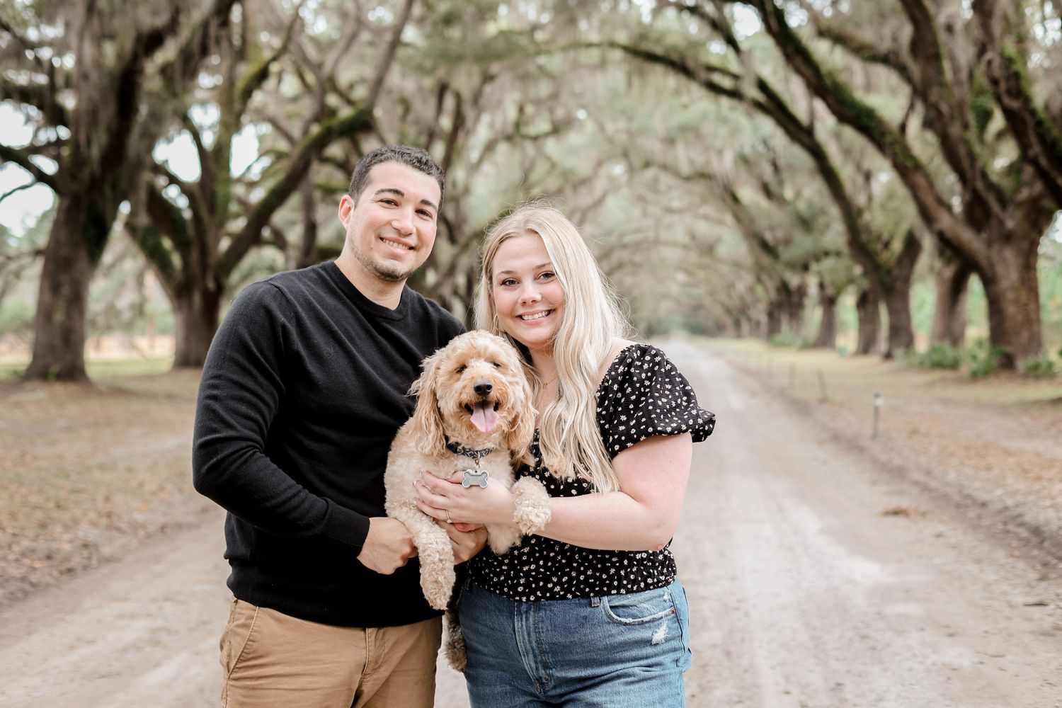 Happy couple with their small fluffy dog at a scenic outdoor location.