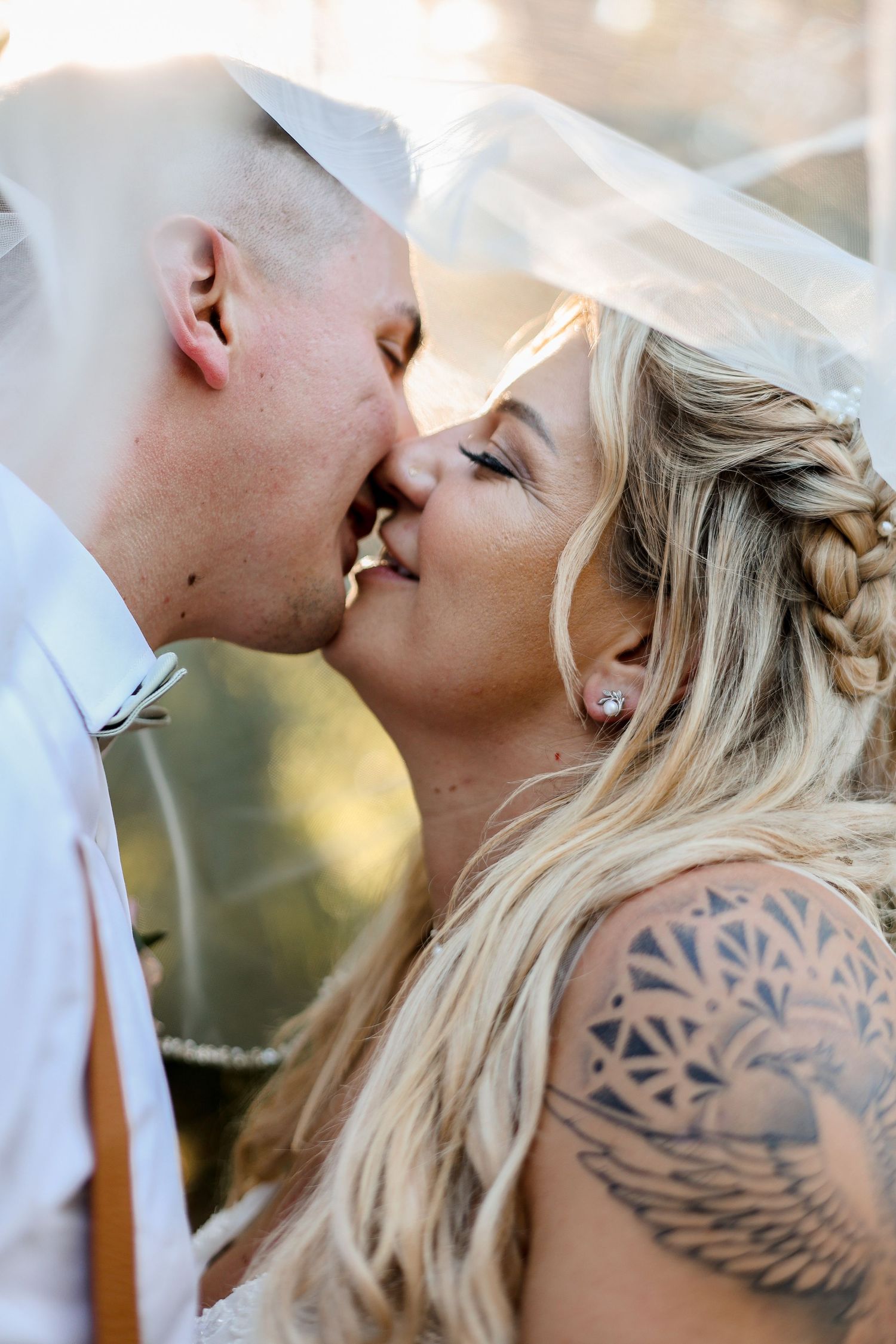 Intimate wedding portrait showing couple kissing with a visible geometric tattoo.