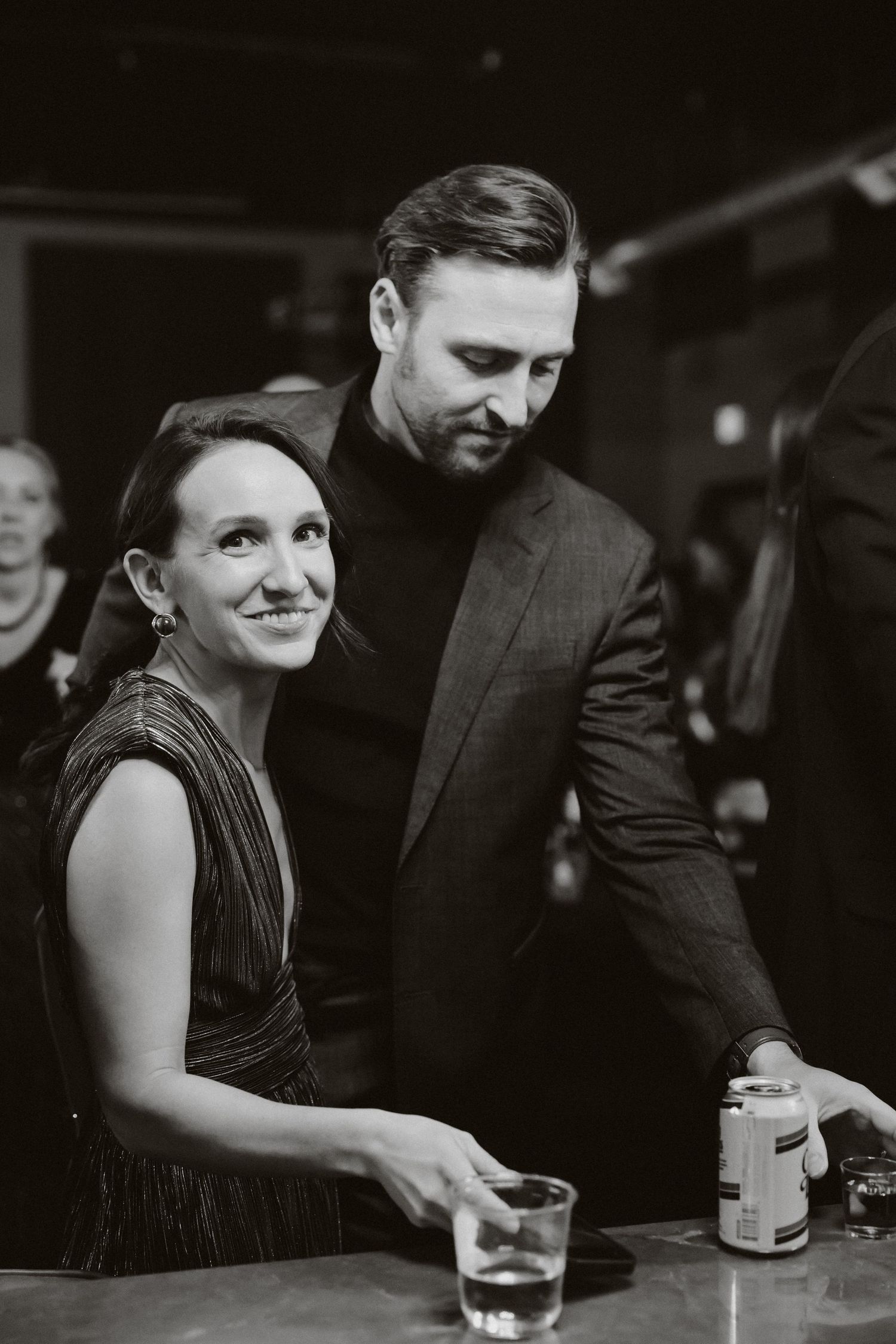 Black and white photo of a smiling woman and man in formal attire at an elegant evening event.