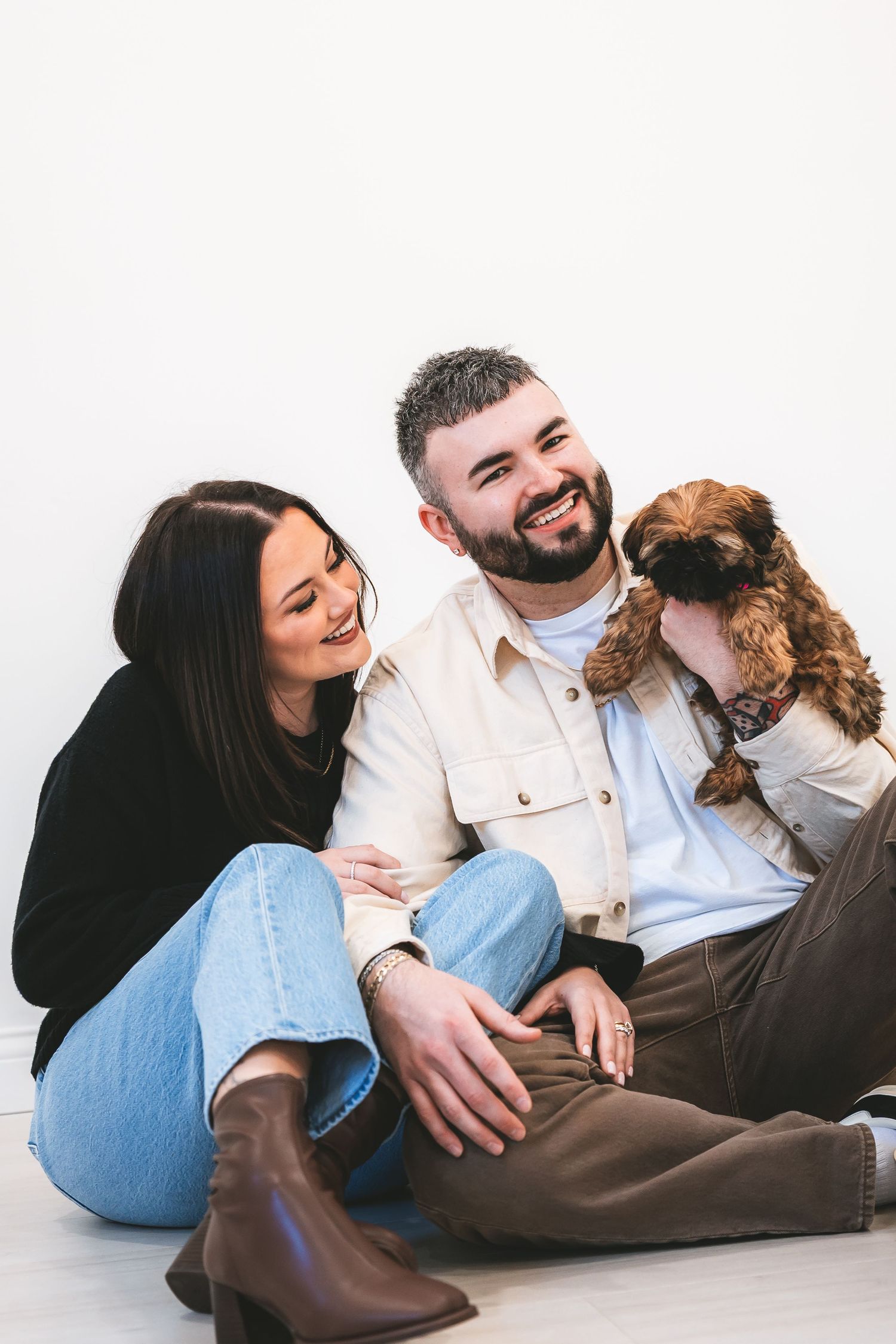 A couple relaxes on the floor with their small brown dog in a series of playful candid photos.