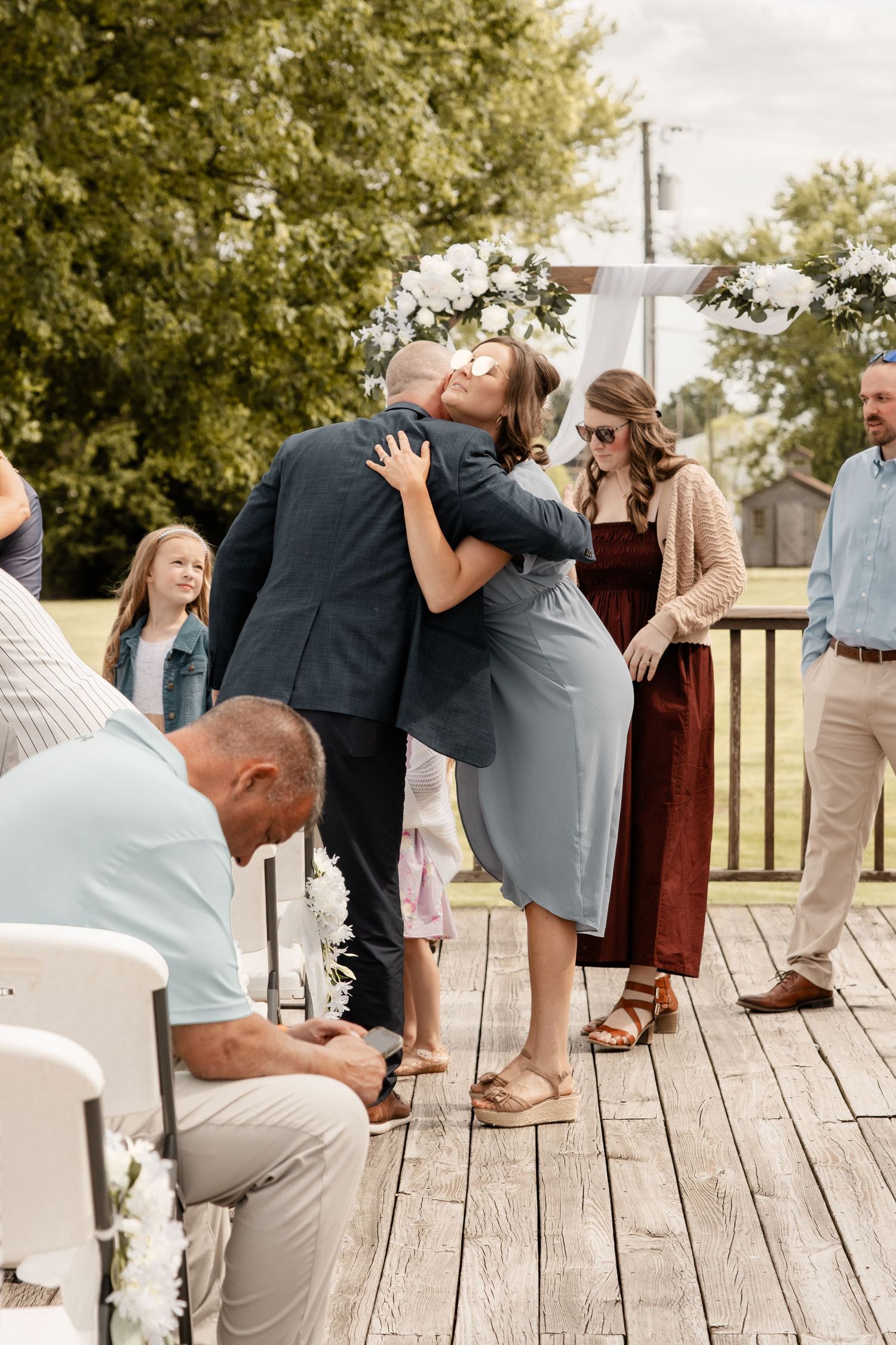 Guests dancing and celebrating together on a rustic wooden deck during an outdoor event.