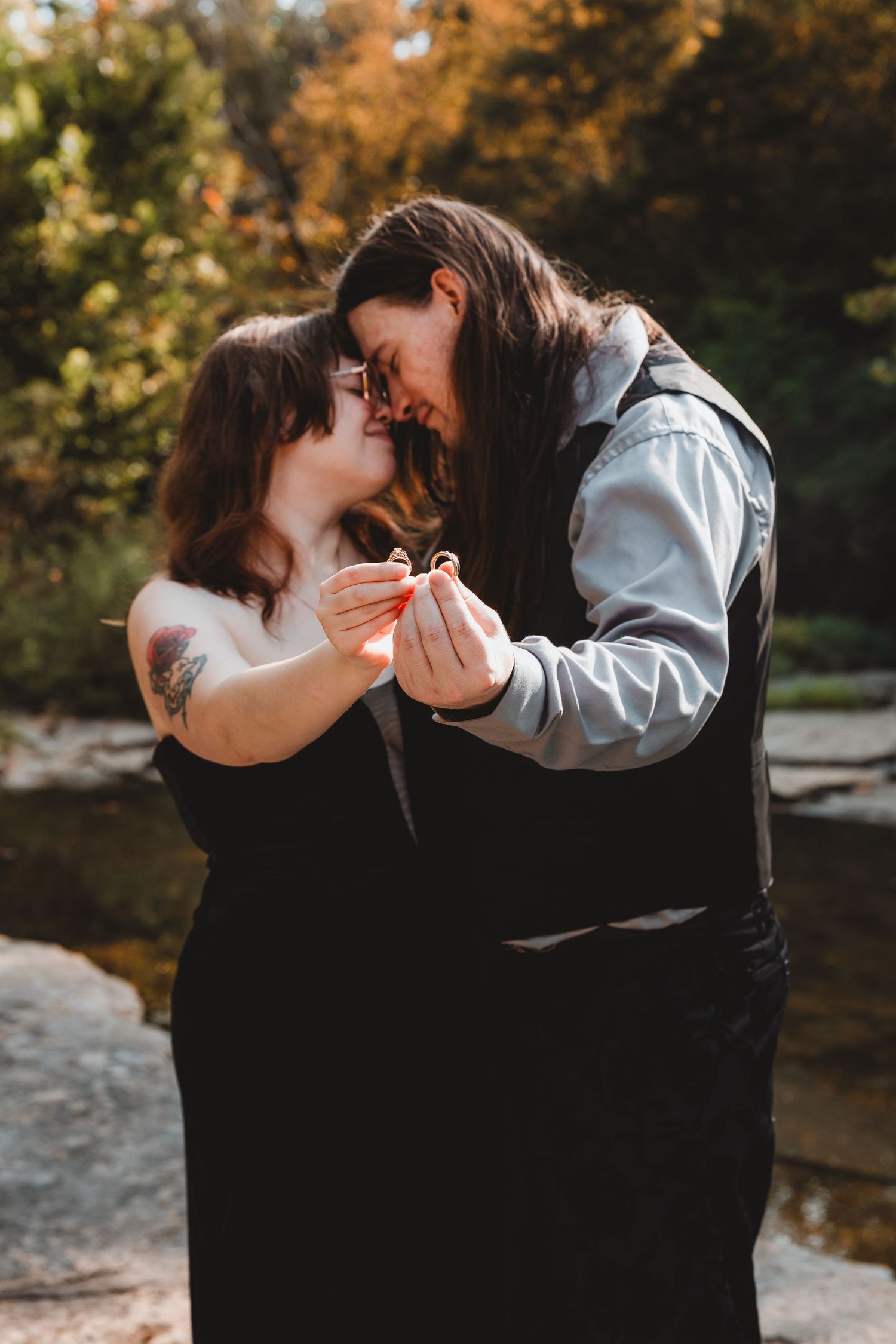 A romantic couple shares an intimate kiss outdoors during autumn with golden foliage in the background.