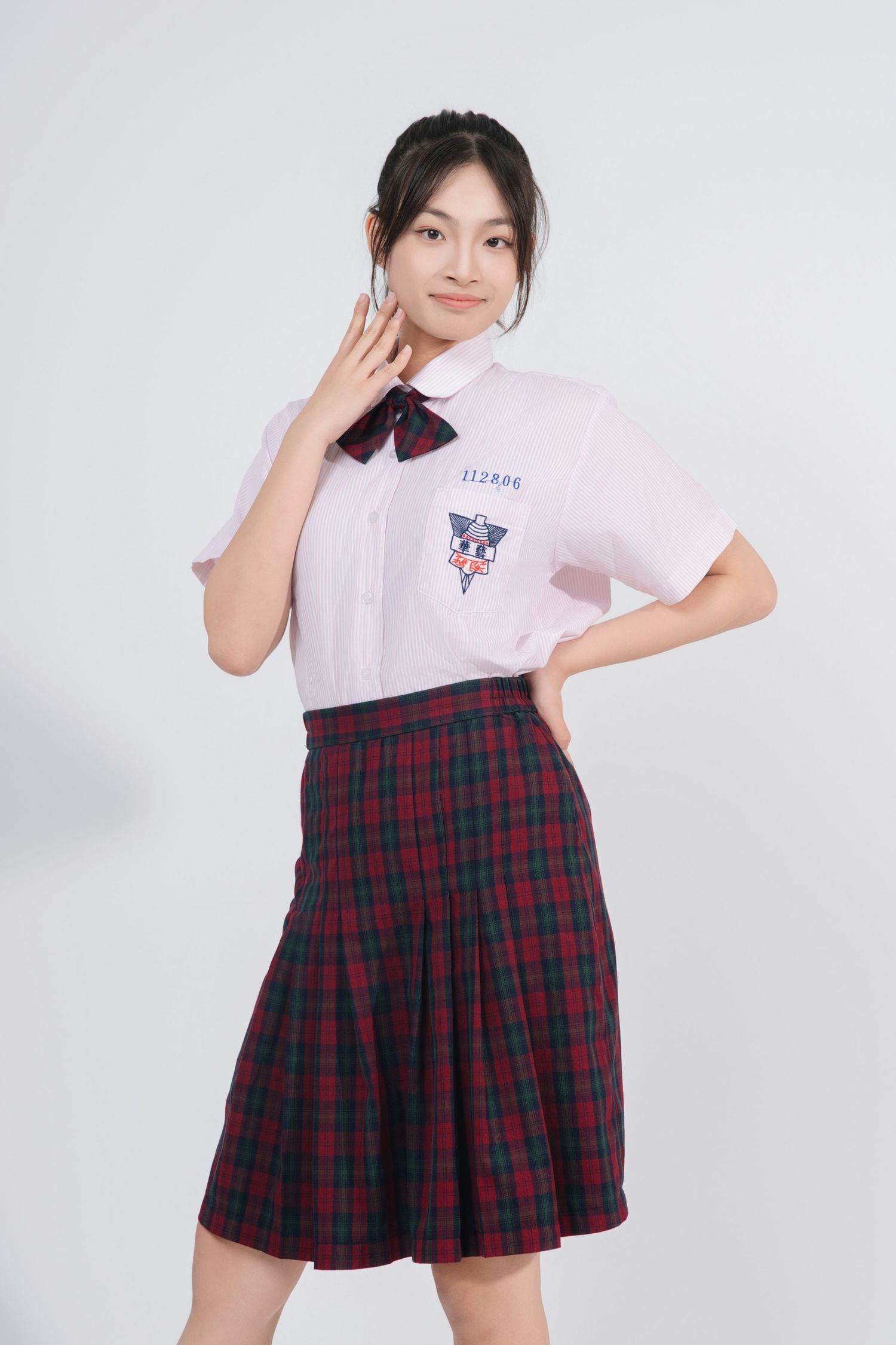 A pink polo shirt paired with a red and navy plaid pleated skirt creates a preppy school uniform look.