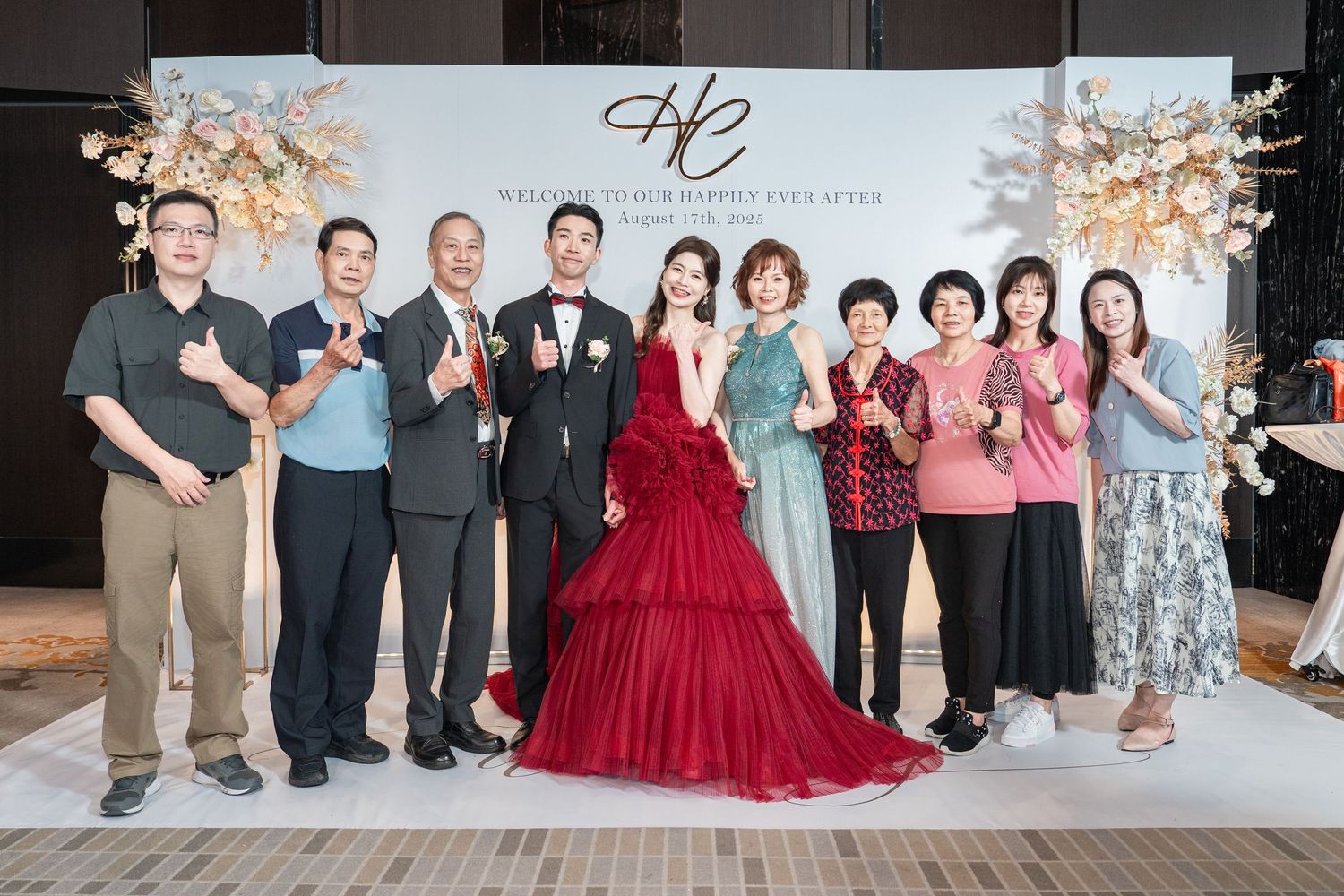 Wedding party group poses together in front of a decorative backdrop at an elegant reception celebration.