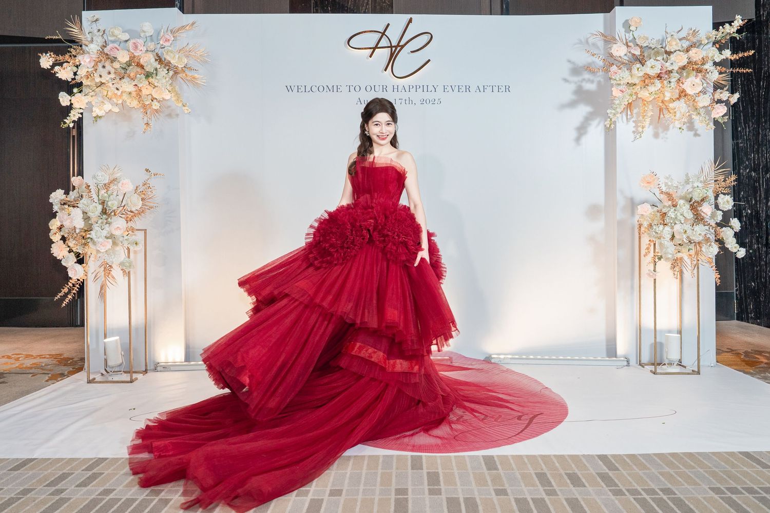 Elegant flowing red tulle gown in sequence showing dress movement against a white studio backdrop with floral decor.