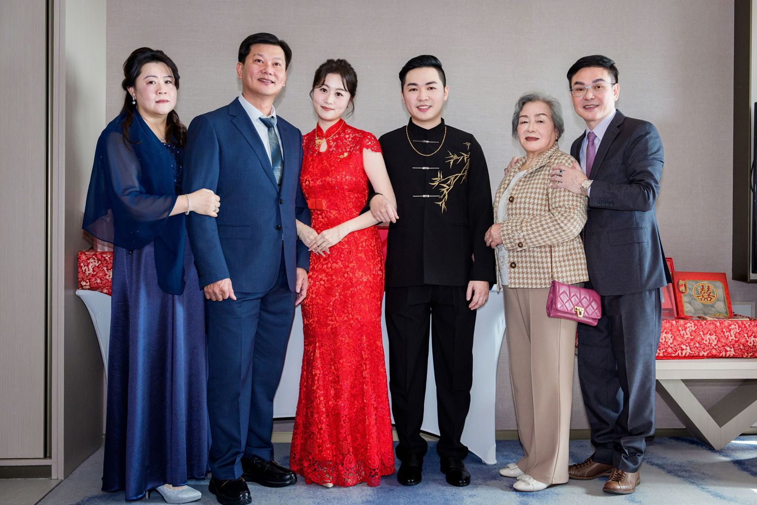 A group of people in formal attire pose together at an elegant indoor event space.