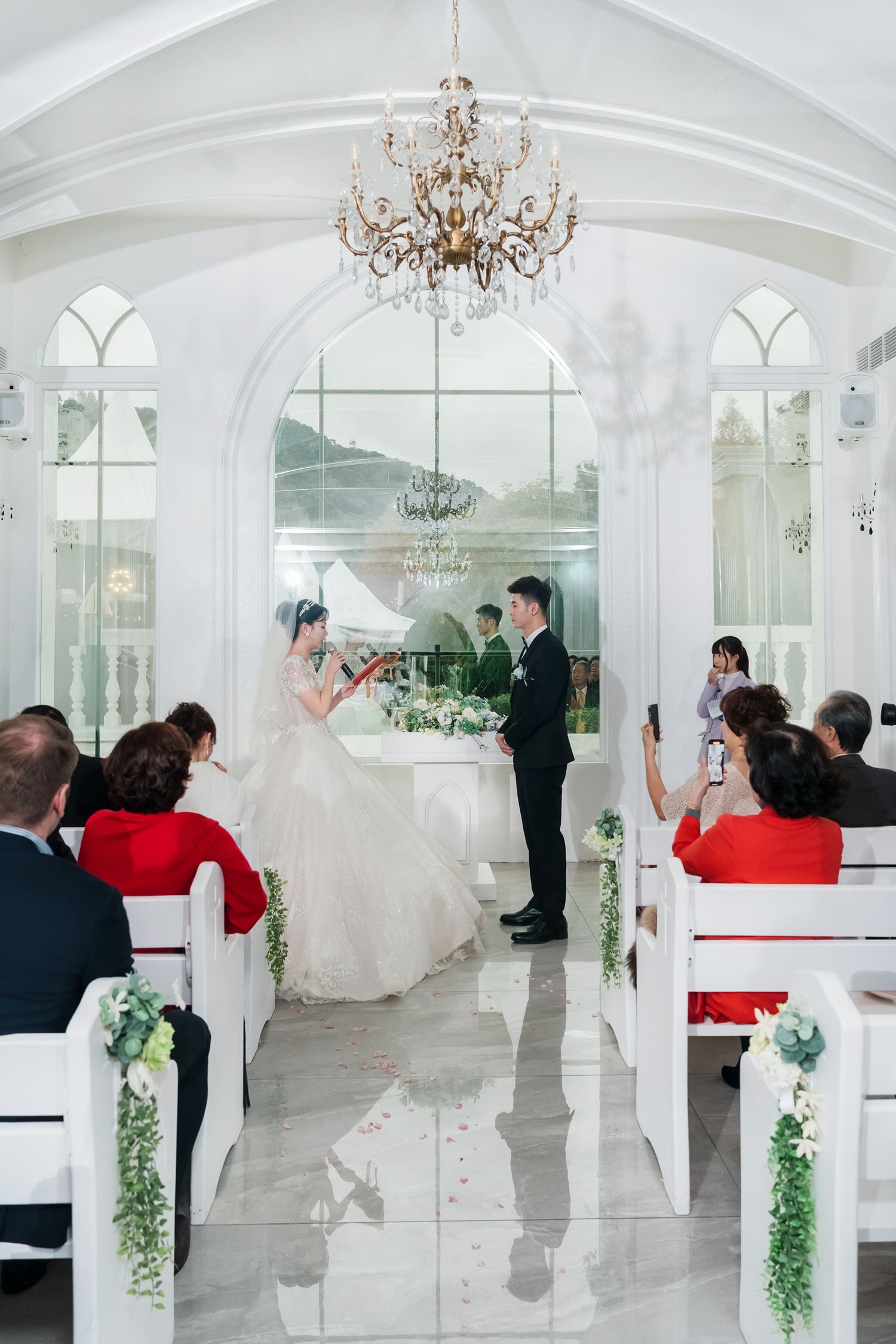 A sequence of wedding photos showing a couple dancing in an elegant white ballroom with chandeliers and arched windows.