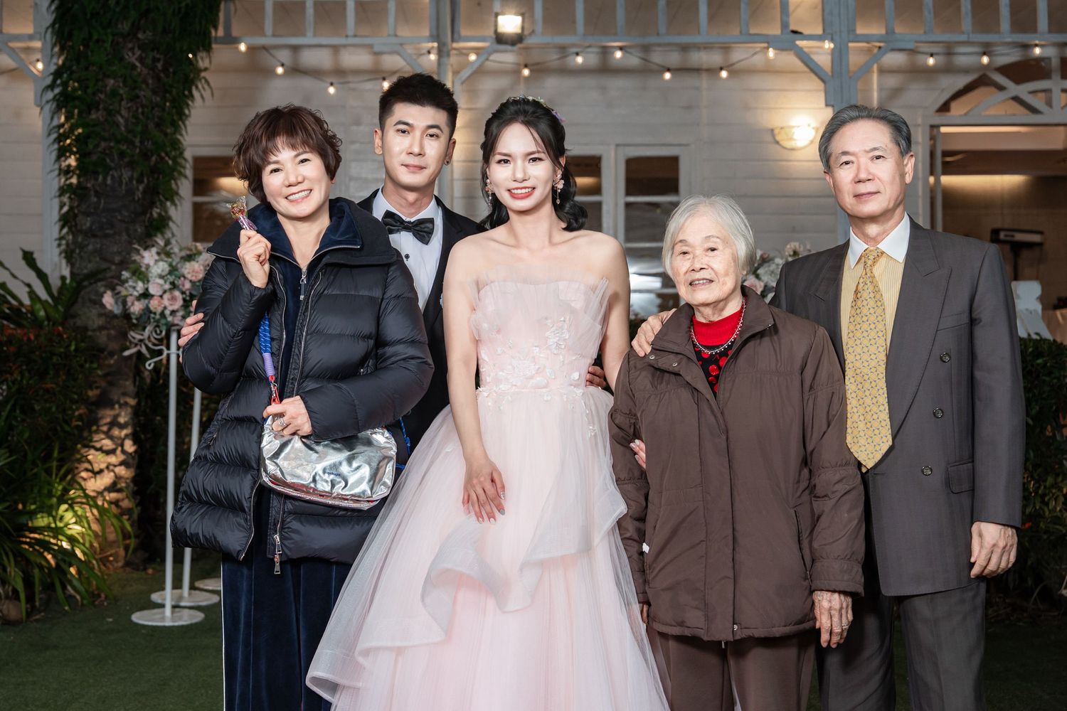 A group of people pose together at a formal event wearing elegant evening attire and suits.