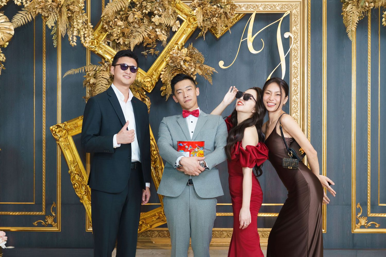 Celebratory group poses with movie popcorn against ornate blue and gold wall in formal attire.