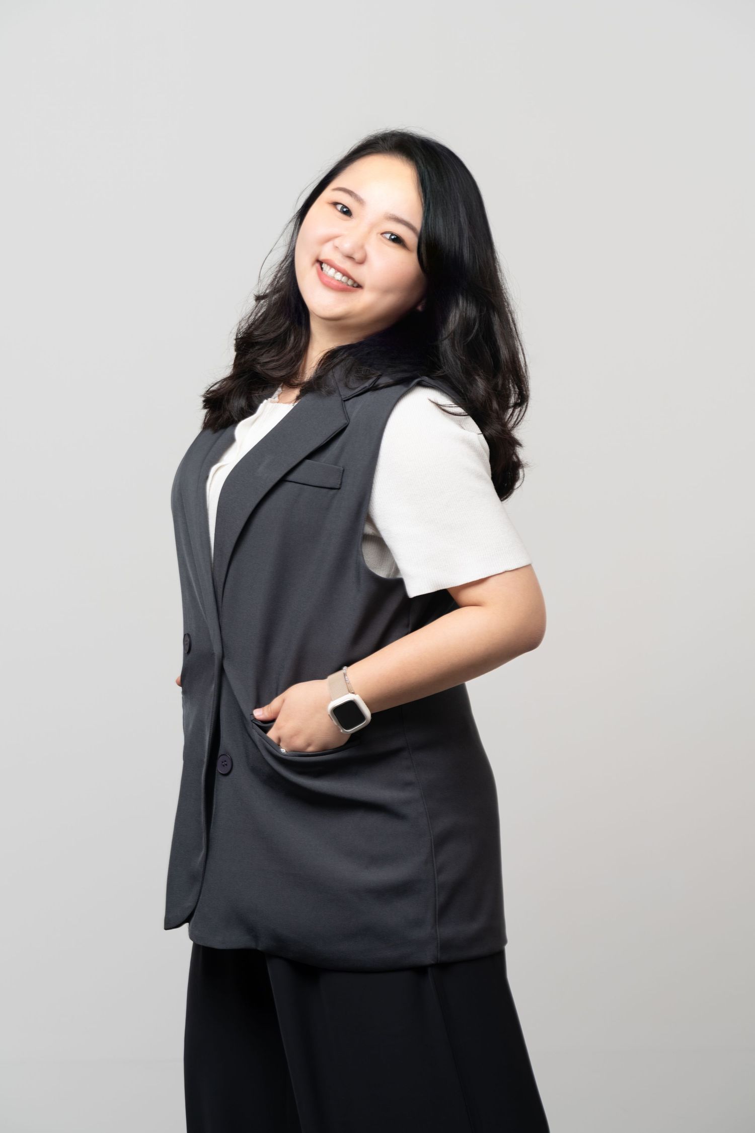 A professional in a gray vest and white shirt poses confidently against a light gray background.