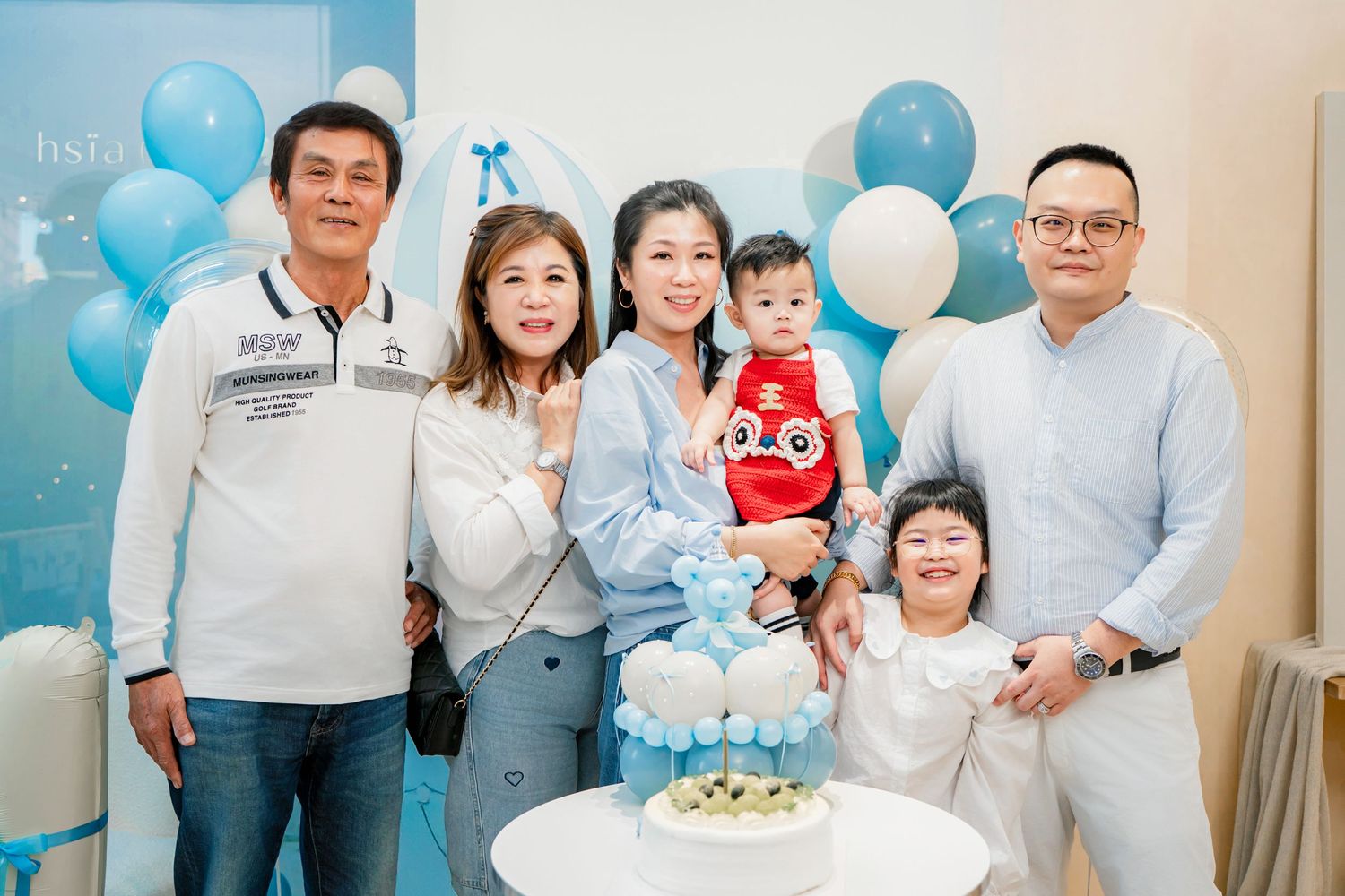 Blue and white balloon decorations fill a room during a family celebration.