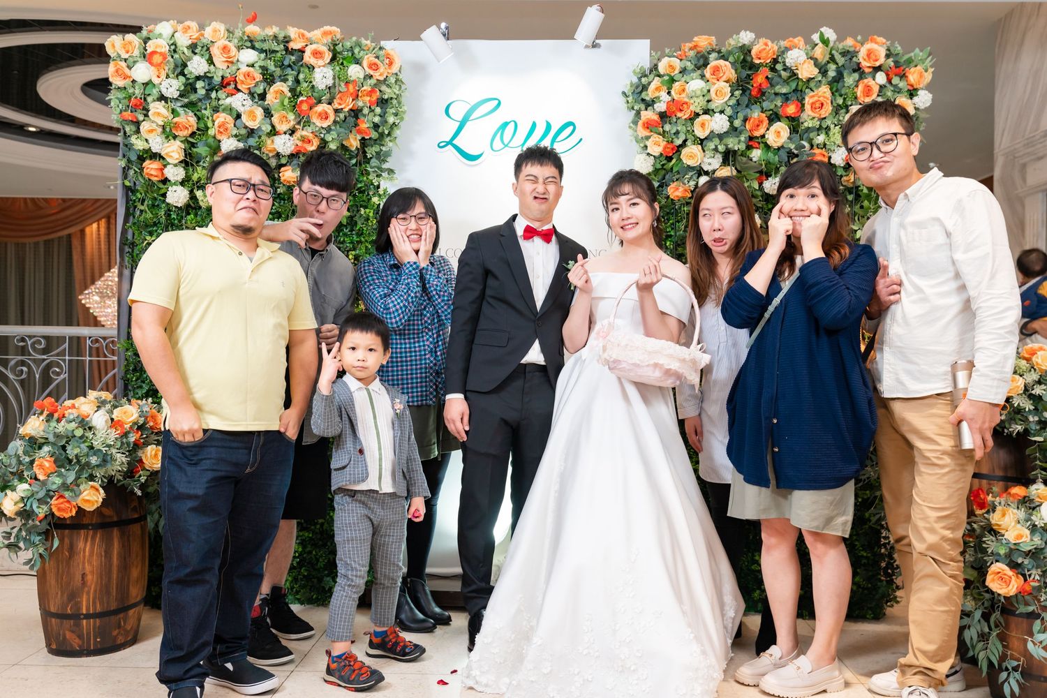 Wedding celebration gathering with family members posed before a decorative flower wall.