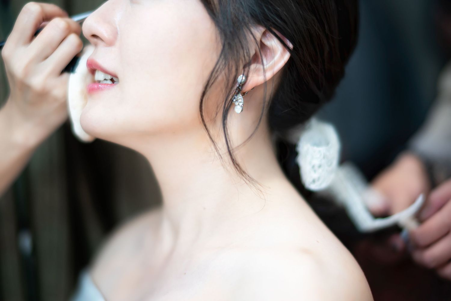 Close-up shot of a bride getting her makeup done with soft lighting and shallow depth of field.