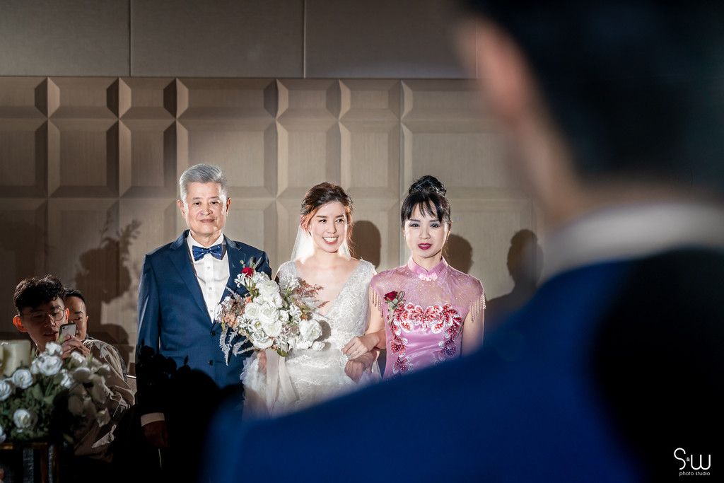 Wedding procession in formal attire during indoor ceremony.