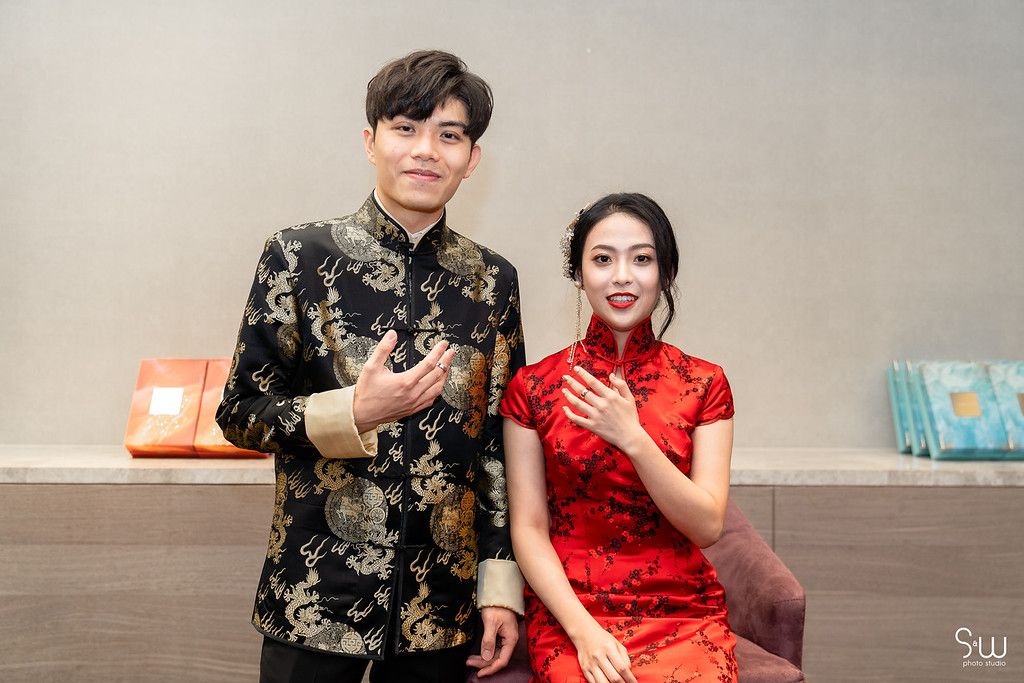 A couple in traditional Chinese formal wear poses together during a wedding ceremony.