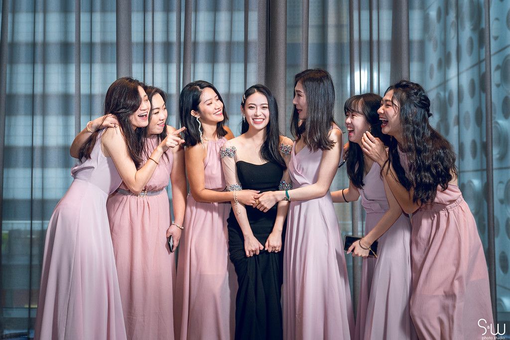 Bridesmaids in pink dresses sharing a joyful moment together at a wedding celebration.