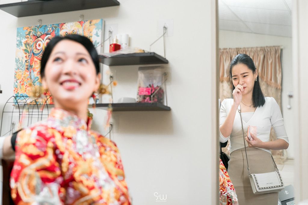 A candid photo showing a reflection in a mirror of someone wearing a red traditional Chinese dress.