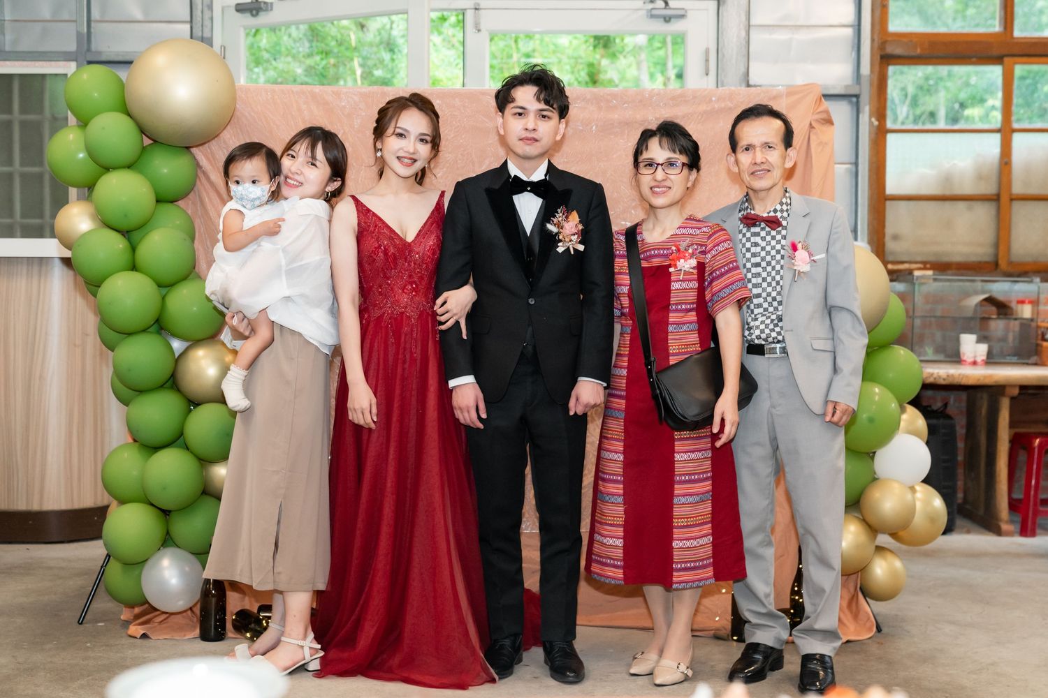 Formal event photo with green balloon arch and decorative backdrop.